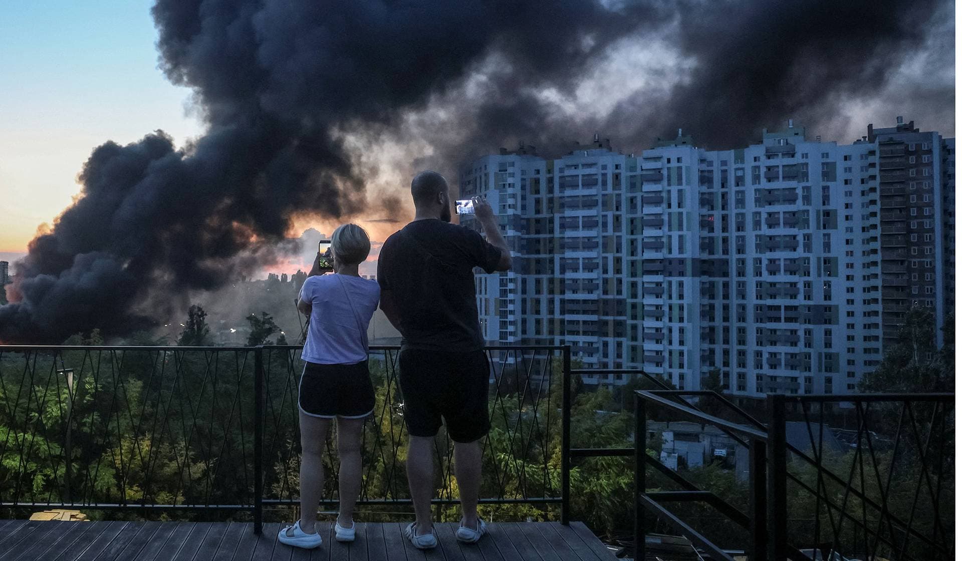 Residents take pictures as smoke rises in the city during a Russian drone strike in Kyiv