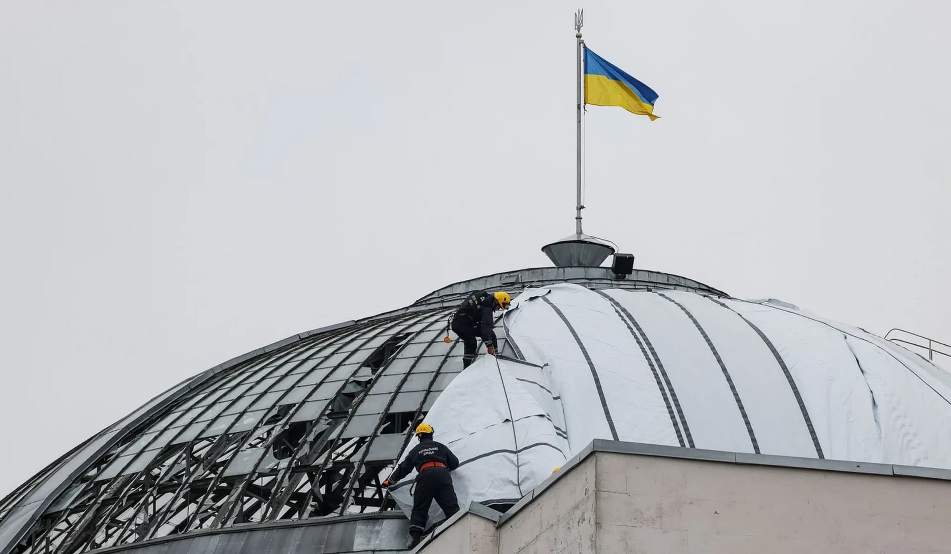 Climbers cover a roof of a historic building damaged over a week ago by Russian missile strike in the center Kyiv