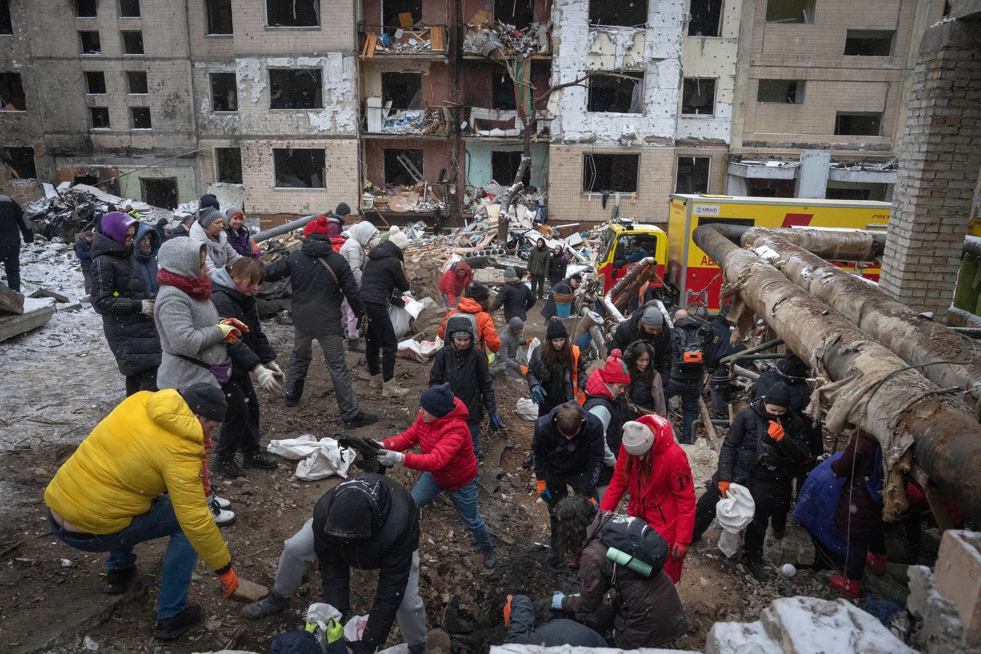 Volunteers and residents clear the debris of an apartment building destroyed after Tuesday Russian attack in Kyiv