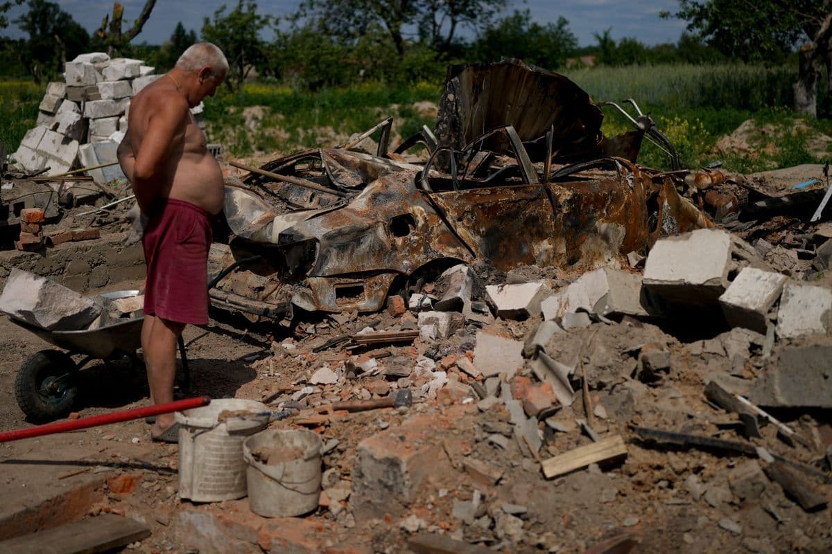A man looks at what is left of his home and car after attacks in Yasnohorodka