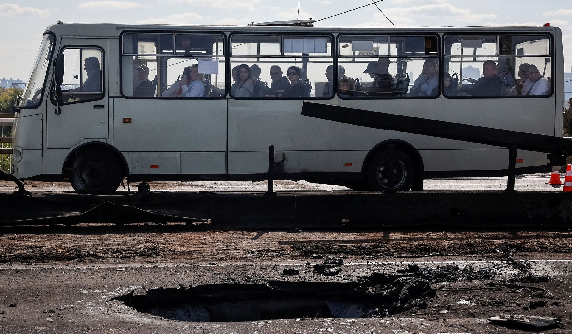 People sit in a bus as they ride at a site of the North Bridge hit by a Russian drone strike in Kyiv, Ukraine, October 4, 2026.
