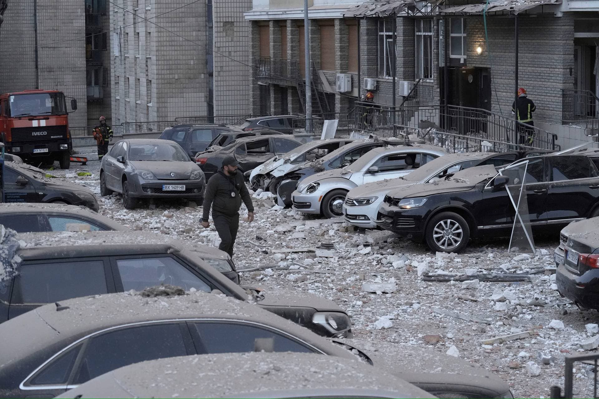 A police officer walks at the parking with damaged cars in front of a multi-story apartment building which was damaged during Russian attack in Kyiv