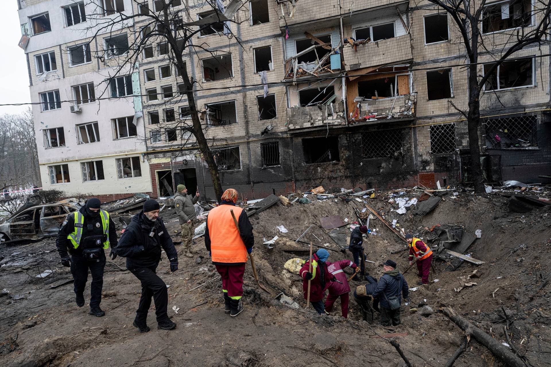 Investigators look for fragments of a rocket inside a crater after a Russian rocket attack at a residential neighbourhood in Kyiv