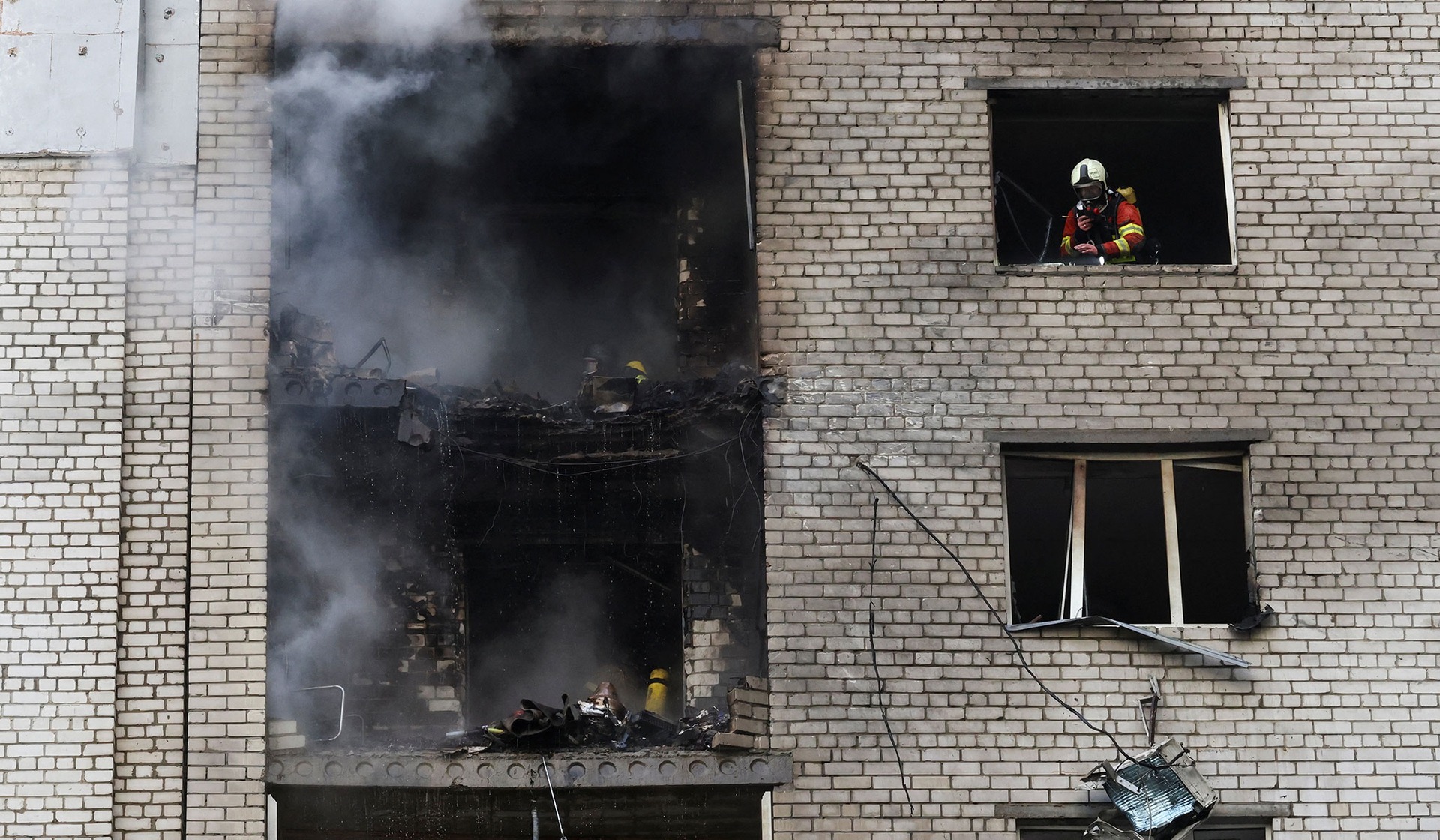 Firefighters work at the site of an apartment building which was hit by a Russian jet drone strike in Kyiv