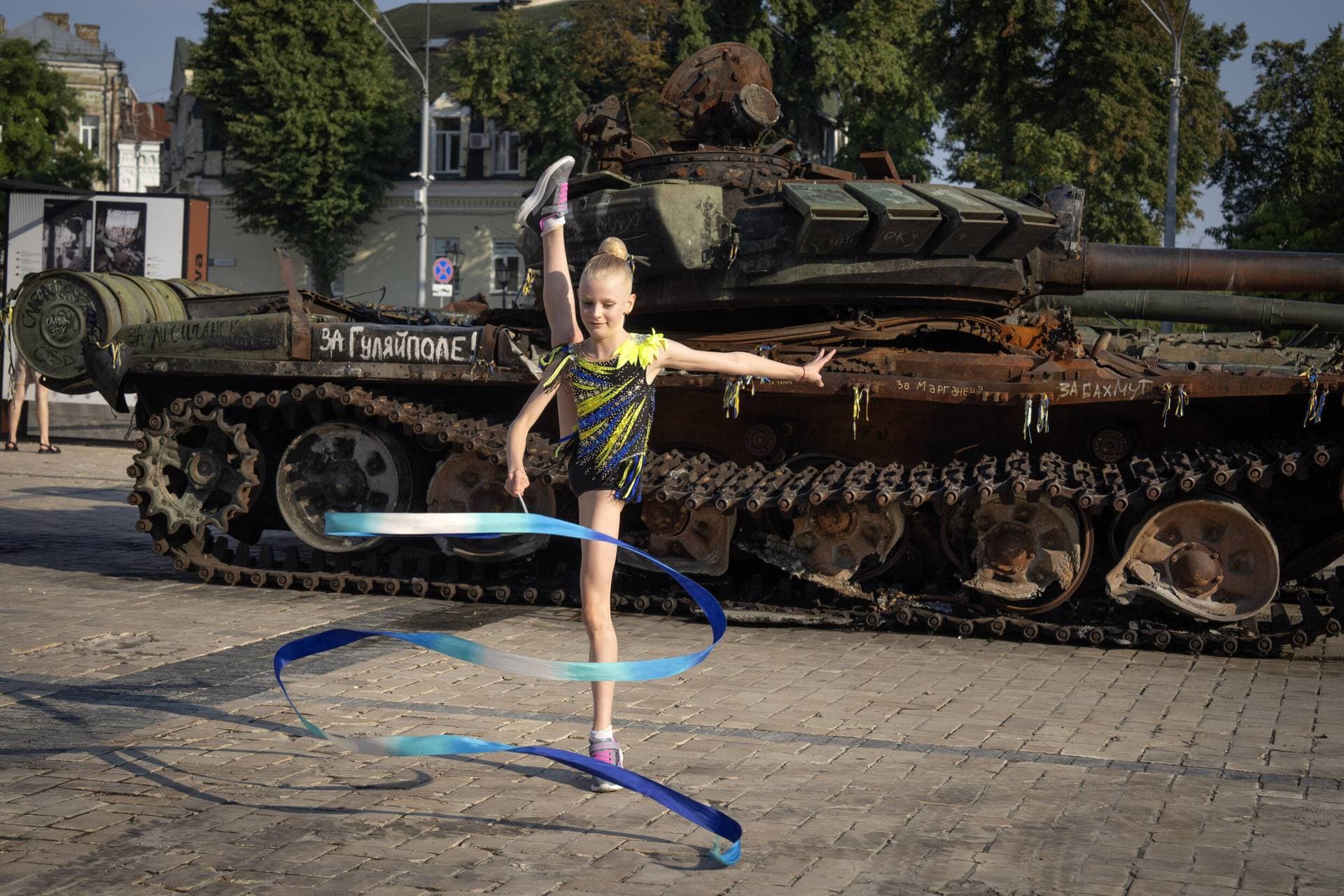 A girl performs near destroyed Russian military vehicles displayed ahead of Independence Day in Kyiv