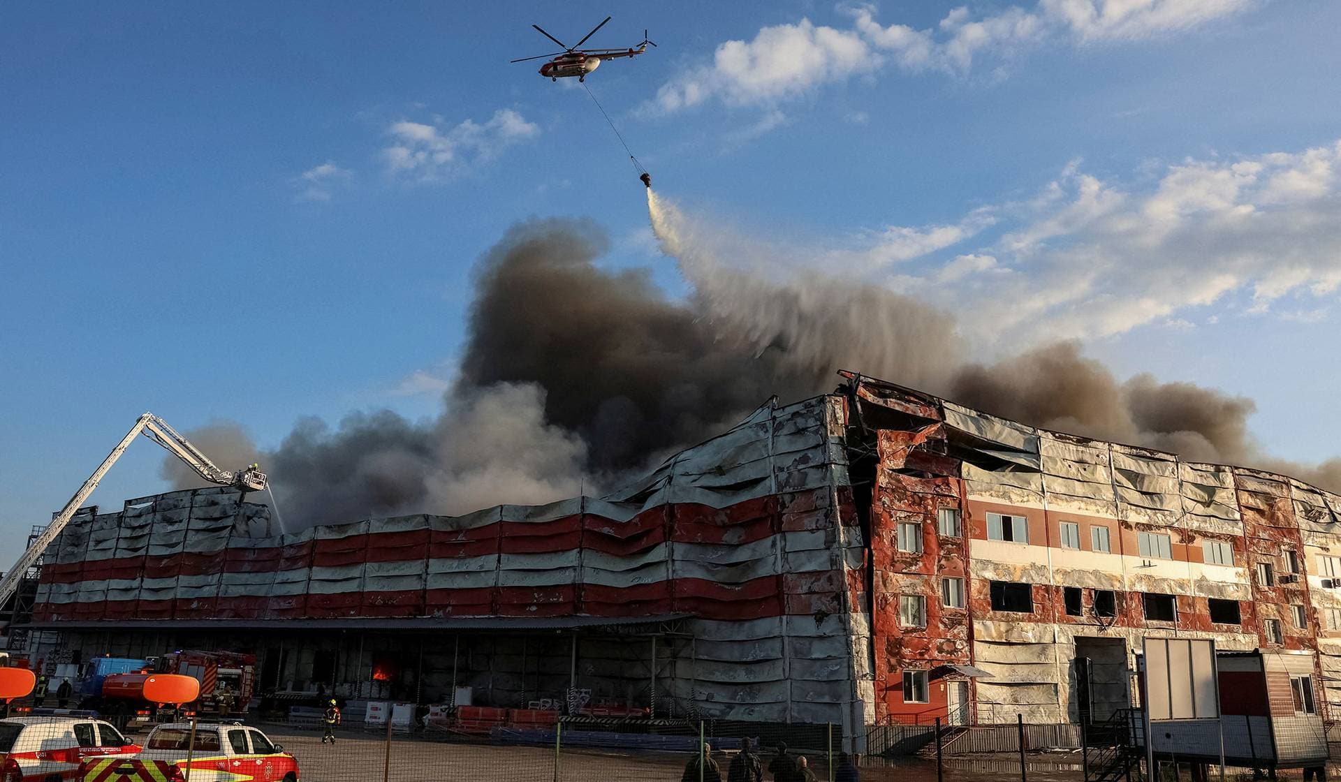A firefighting helicopter drops water over the site of a Russian missile strike in Kyiv Region