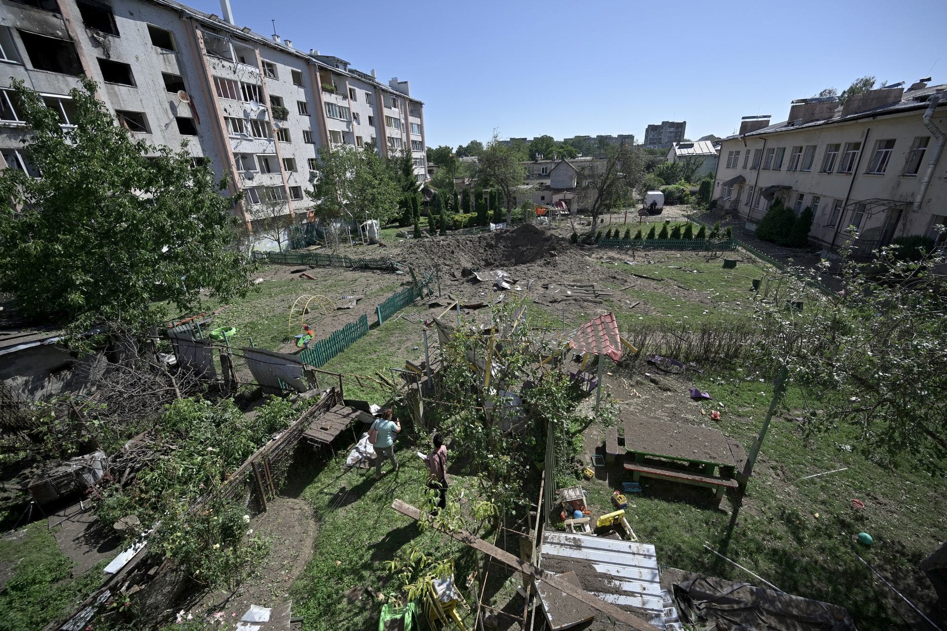 Local residents look at the crater of a missile that fell between residential buildings and a kindergarten in Lviv