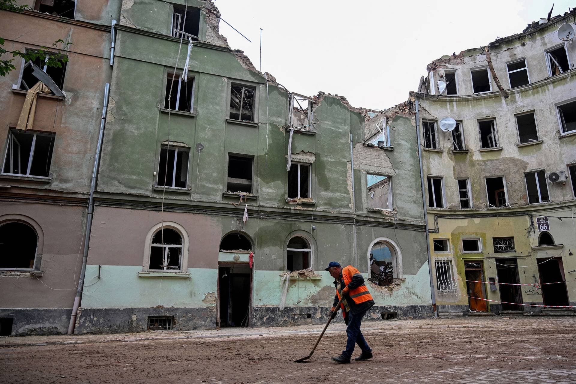 A worker sweeps outside an apartment building destroyed by a missile strike in Lviv