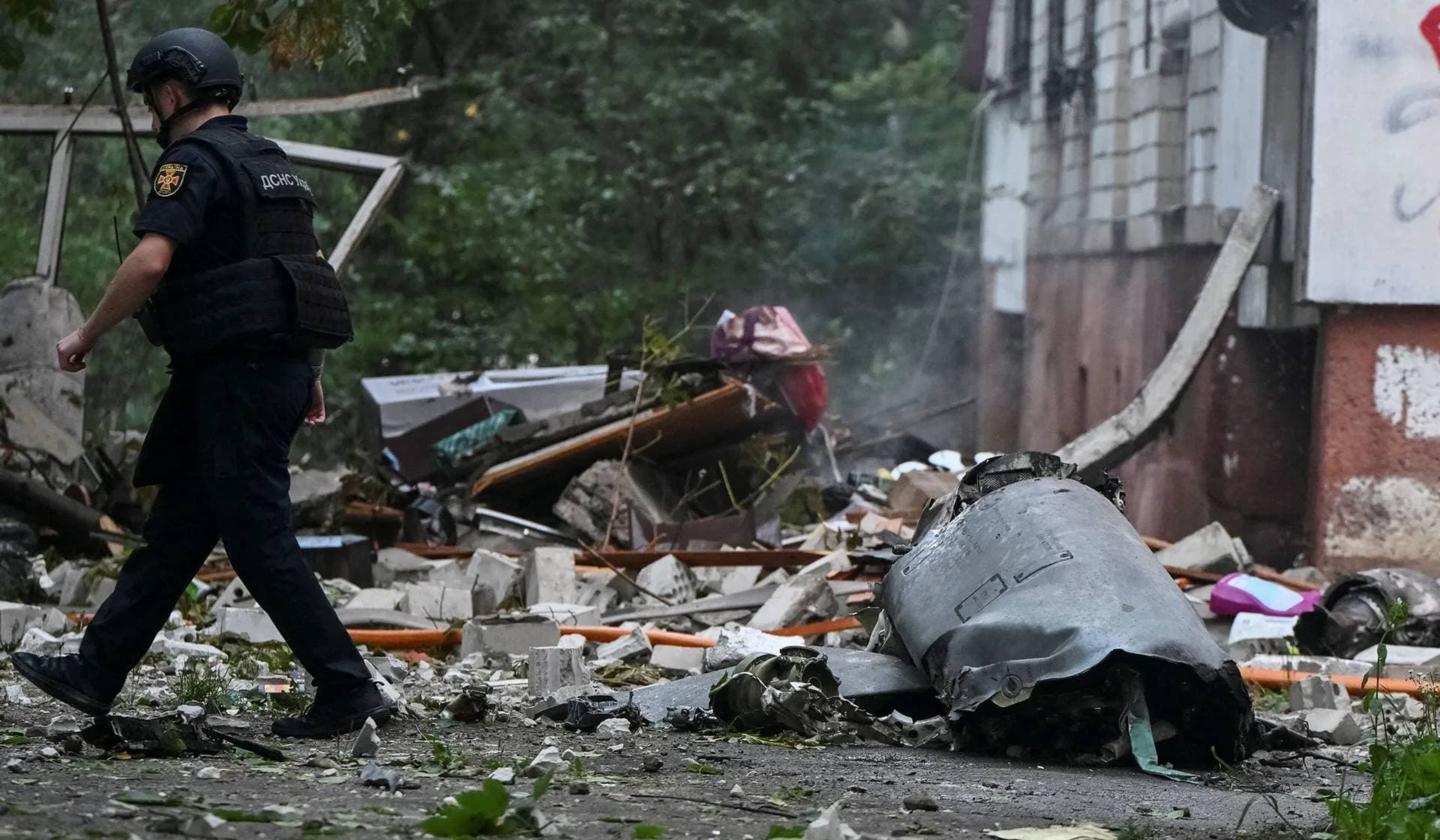 A rescuer walks near a part of Russian cruise missile at the site of an apartment building hit by a Russian missile strike in Lviv