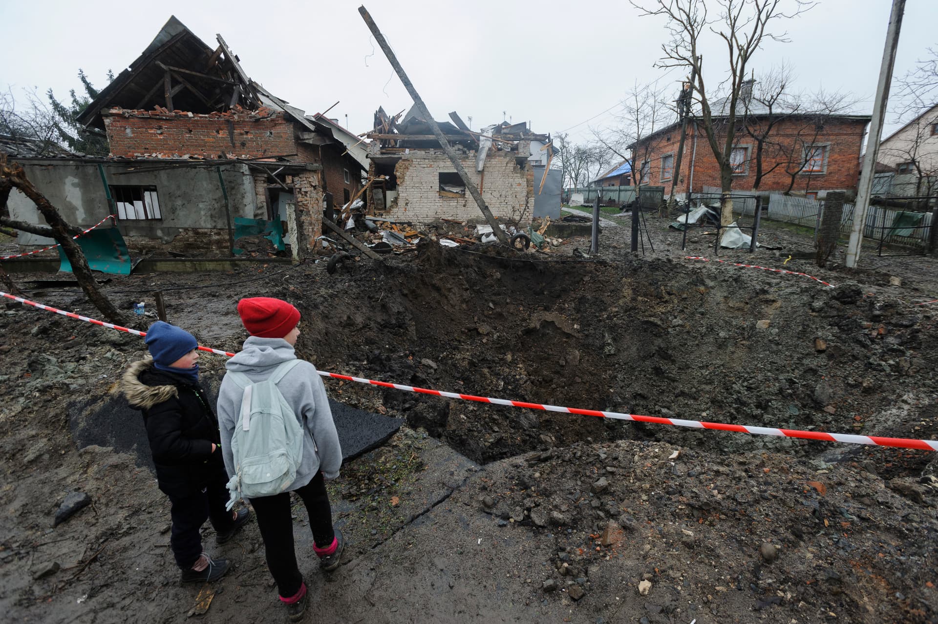 Children look at a crater created by an explosion in a residential area after Russian shelling in Solonka, Lviv region