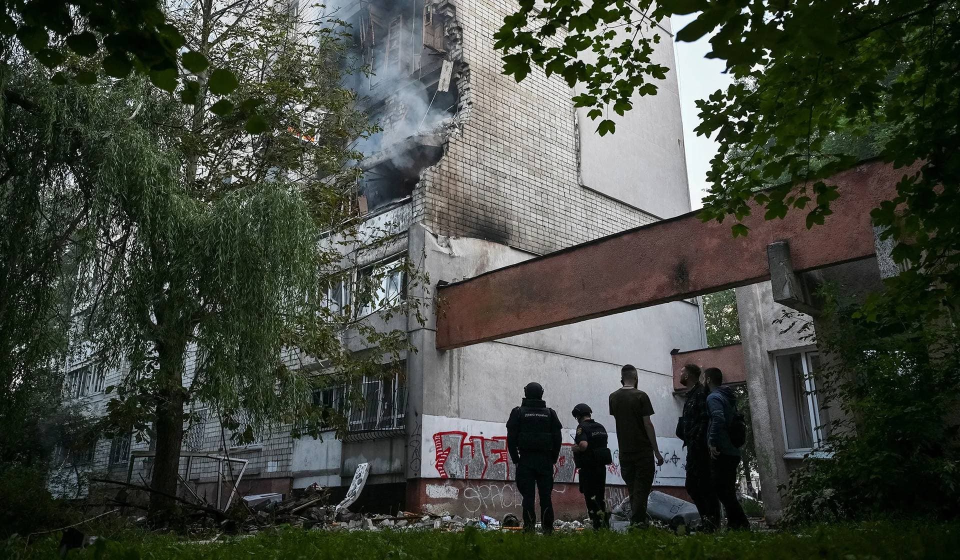 Rescuers and residents stand at the site of an apartment building hit by a Russian missile strike in Lviv