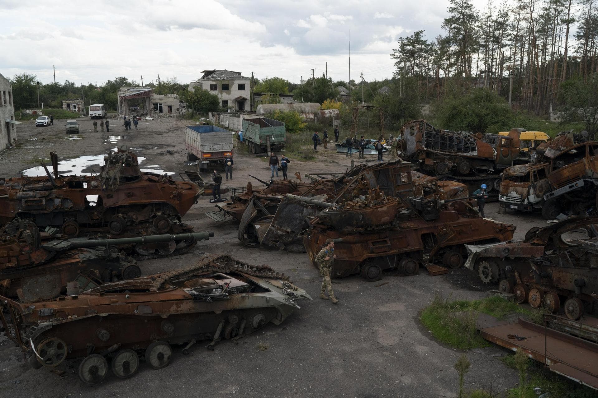 A Ukrainian serviceman and journalists walk between destroyed Russian equipment placed in an area at the recaptured town of Lyman