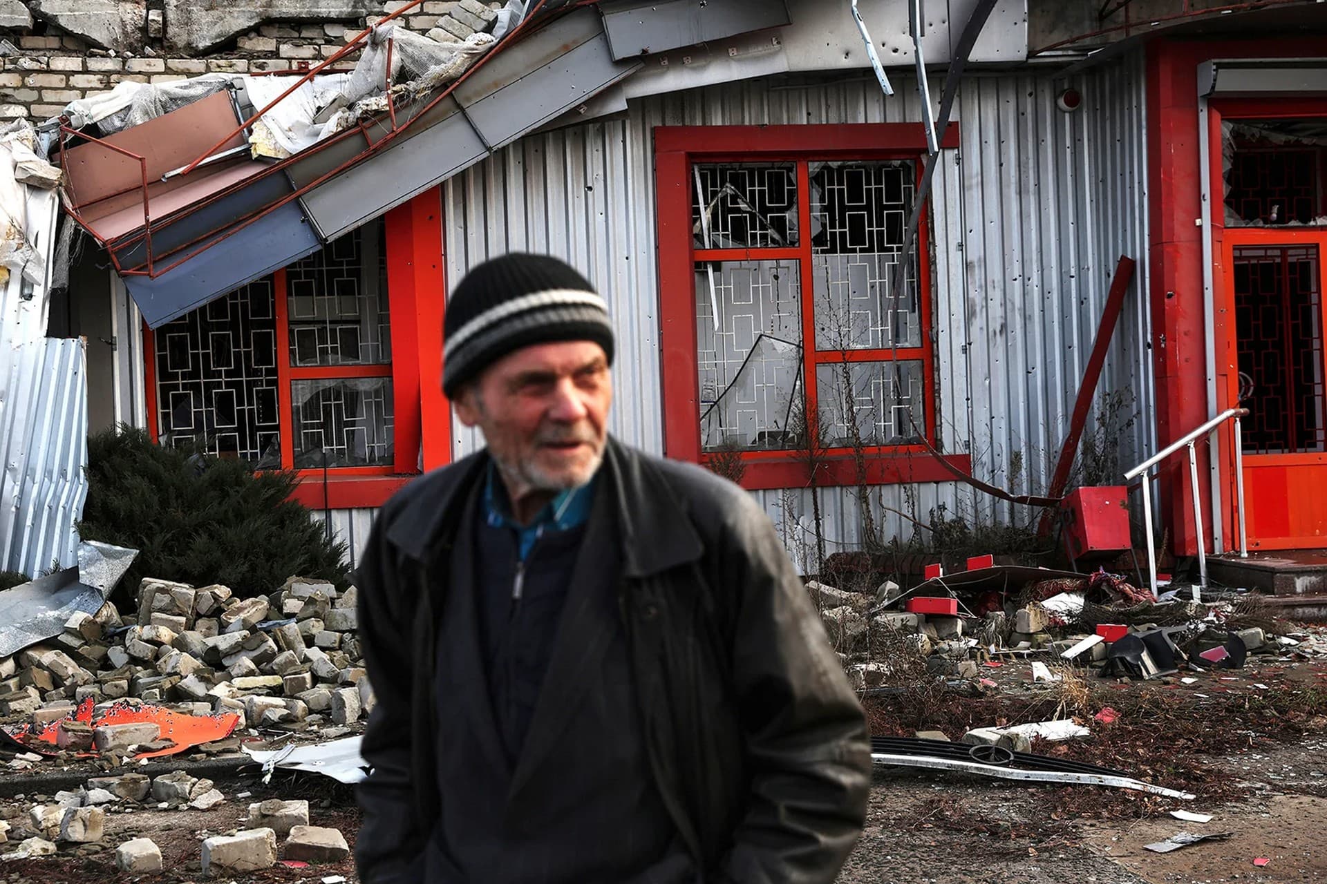 A man walks by a damaged building inside the war-torn town of Lyman