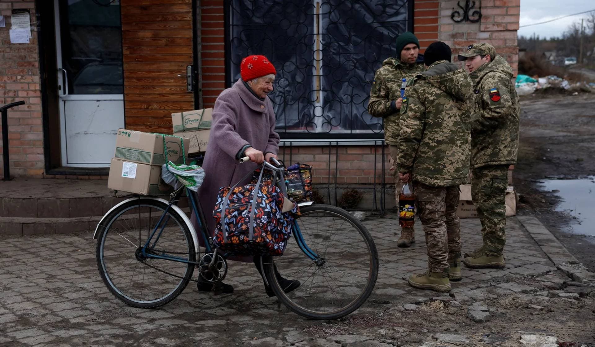 A woman walks with her bicycle carrying boxes of humanitarian aid provided by the Ukrainian military in Yampil