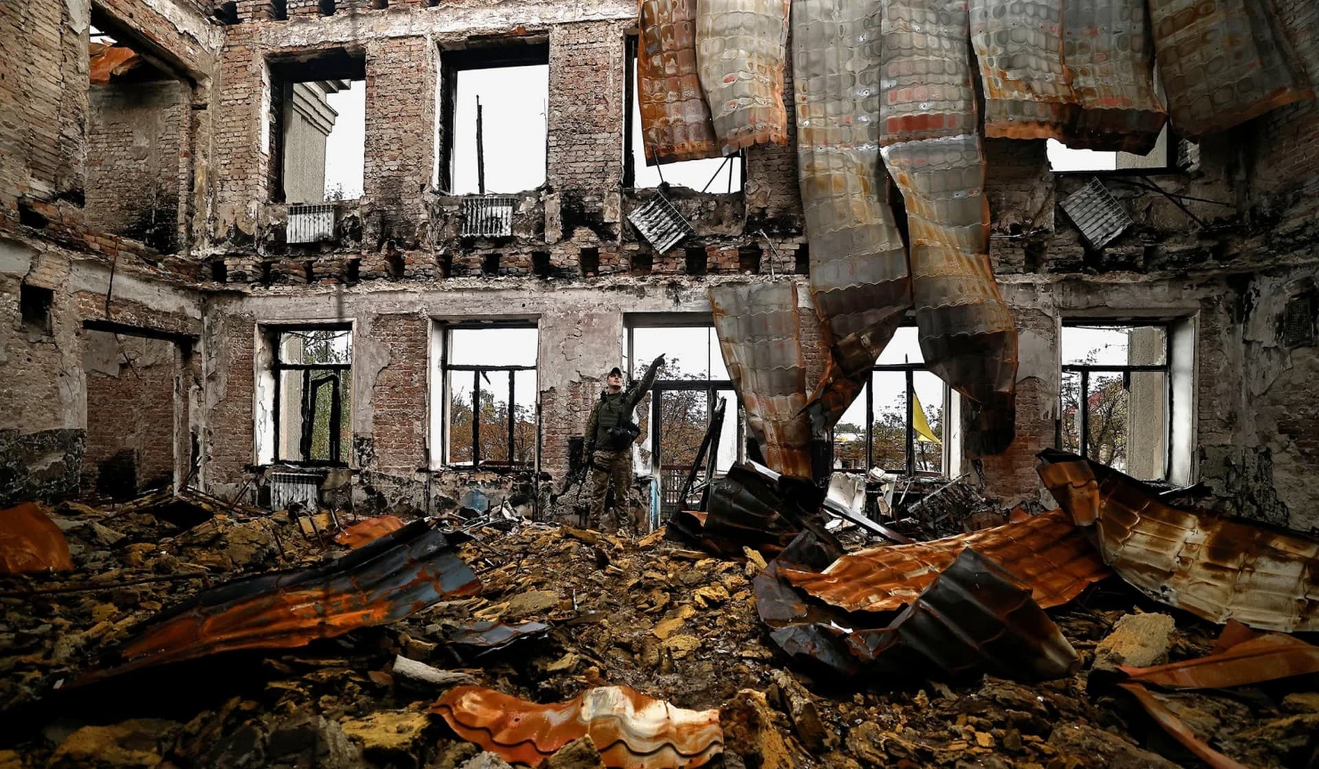 a Ukranian army officer gestures as he stands among the remains of a school in the recently liberated town of Lyman