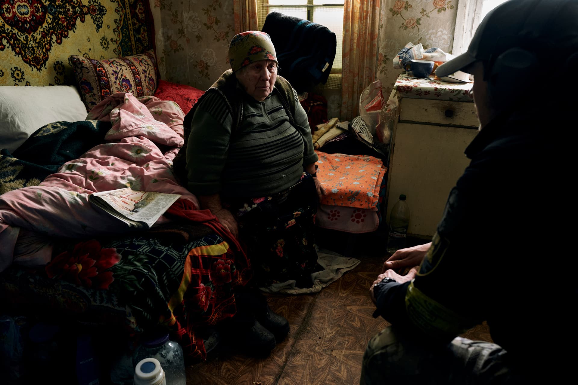 A volunteer urges a local elderly woman to leave her house located in a combat zone in the village of Zarechne