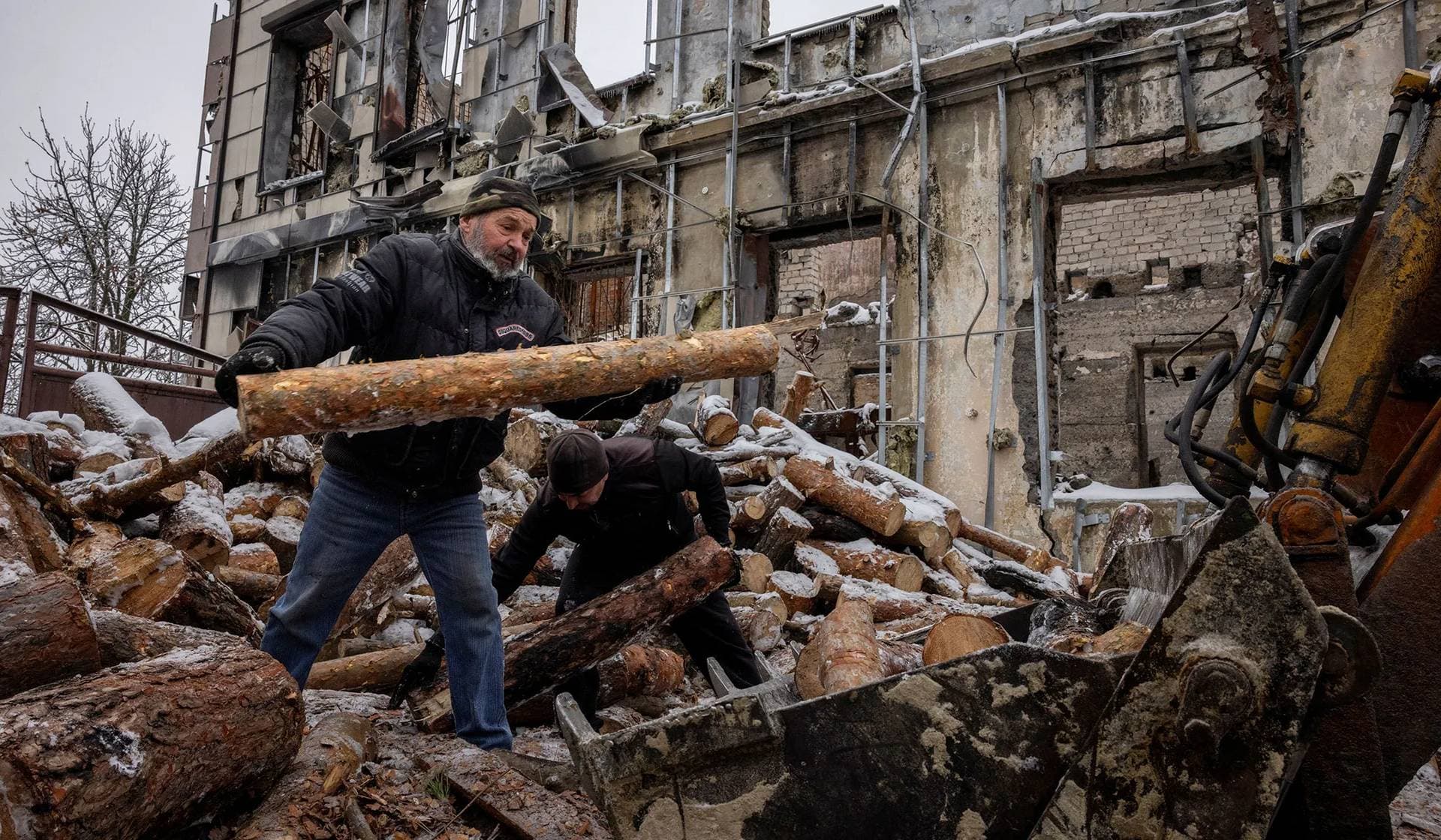 Men pile up wood for homes that are left without heating outside a courthouse that was destroyed by an airstrike in the frontline town of Lyman