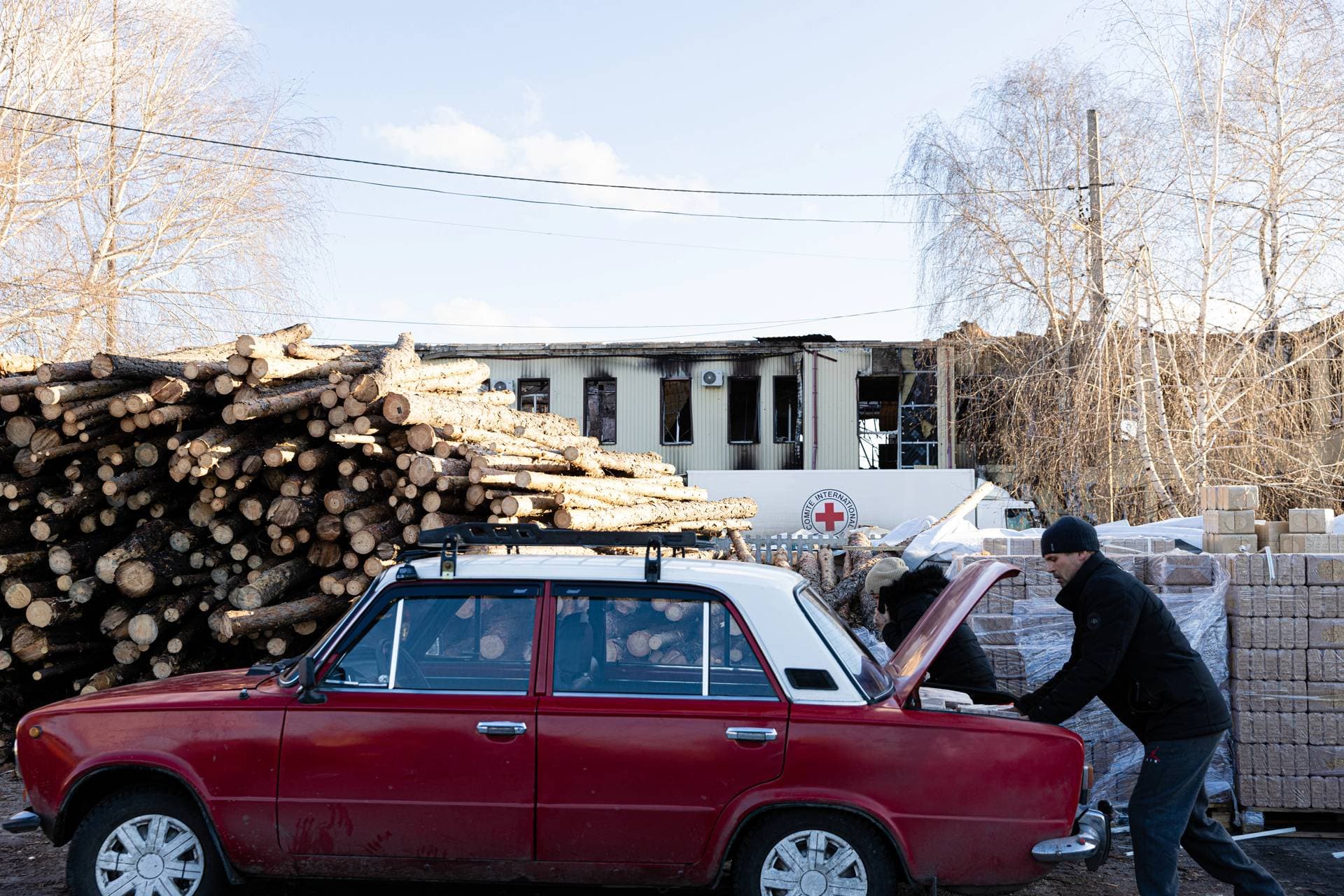 A man loads dry fuel bricks distributed to the residents of Lyman by the Red Cross