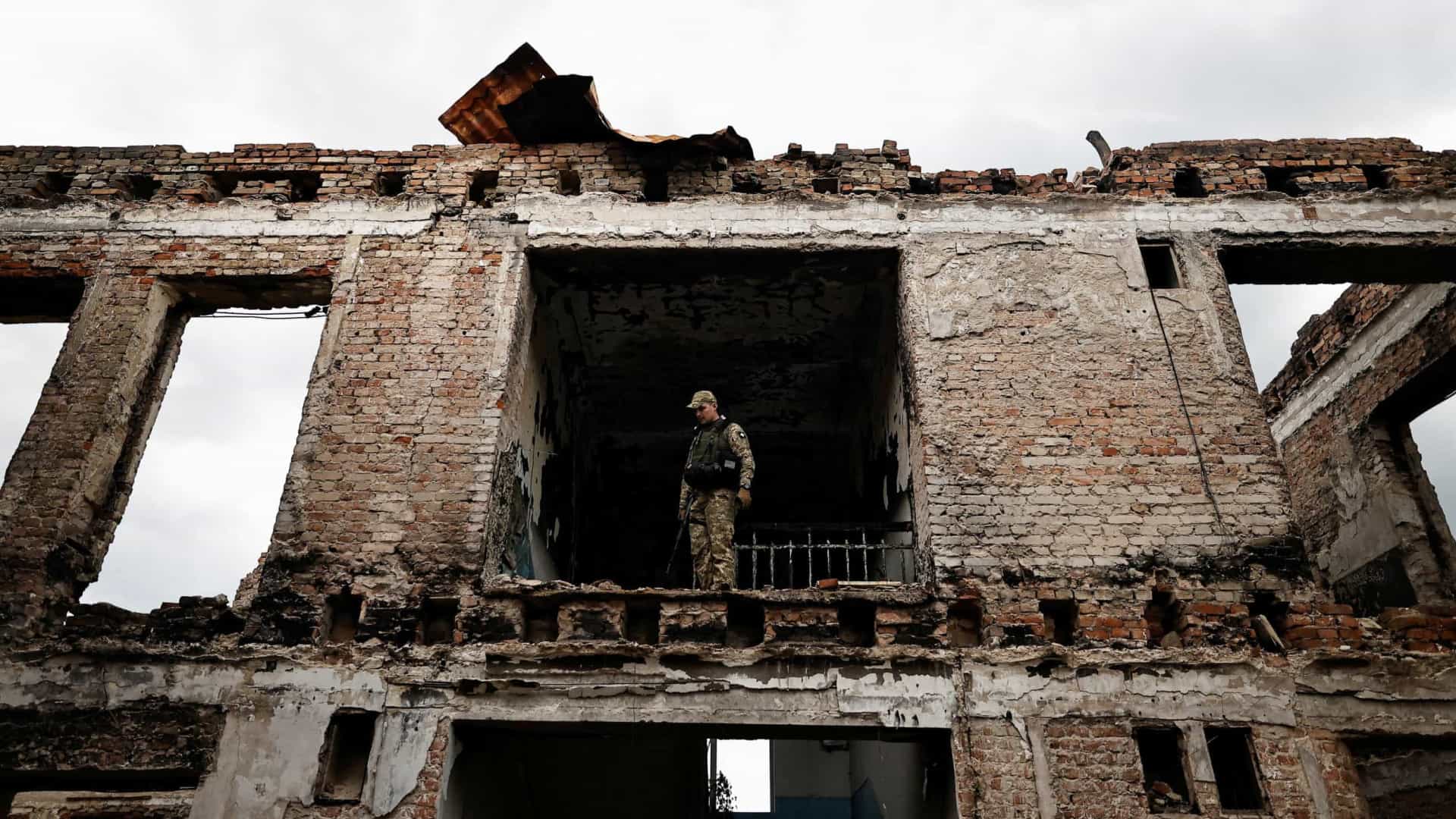 a Ukrainian army officer stands among the remains of a school in the recently liberated town of Lyman