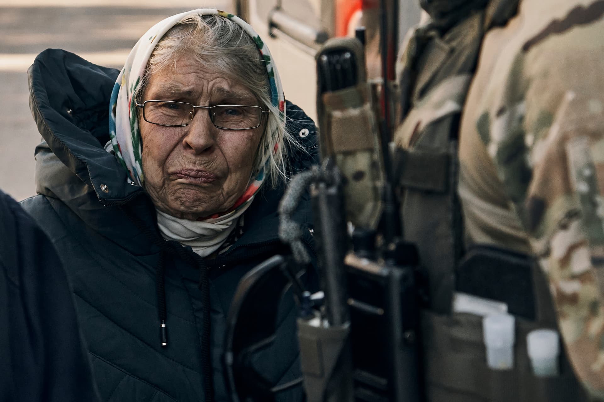 An elderly woman reacts as she leaves her house located in a combat zone in the village of Zarechne