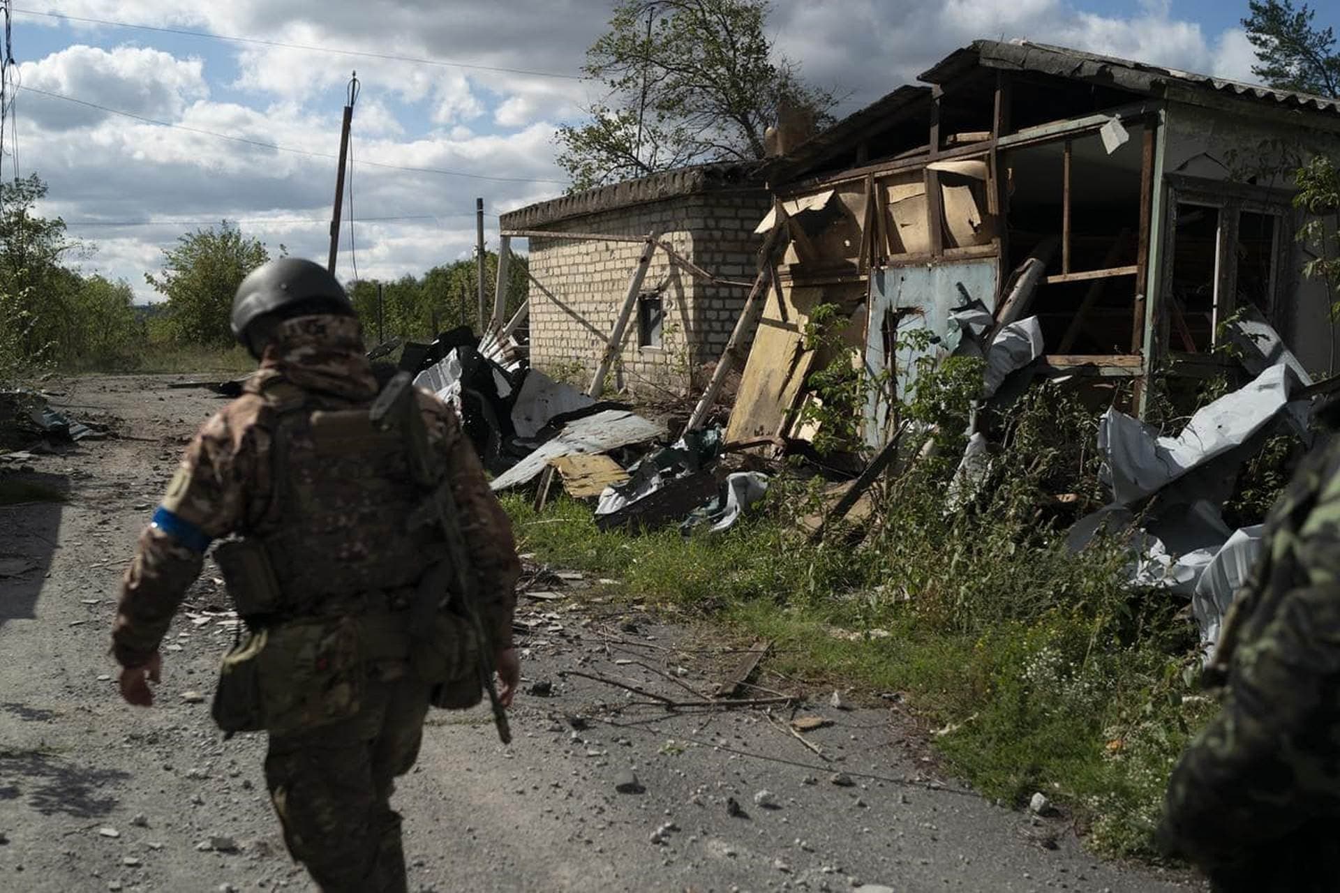 A Ukrainian serviceman walks past a damaged building in the retaken village of Shchurove