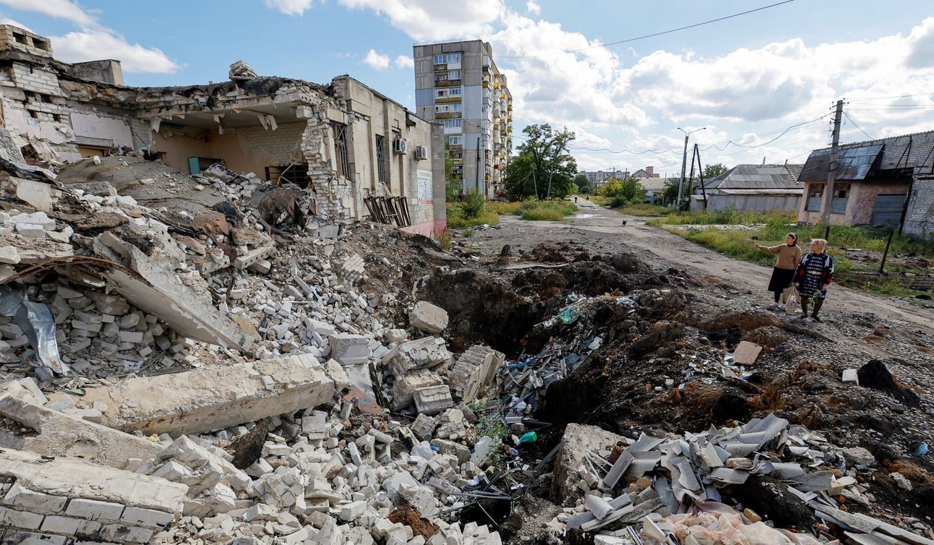 Local residents stand next to the debris of a destroyed building in Lysychansk