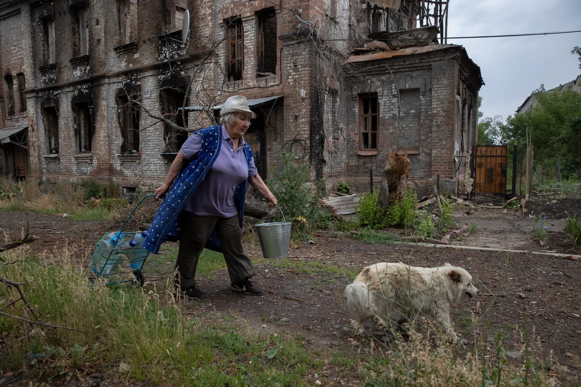 A resident carries water past destroyed buildings in Lysychansk, in the Donetsk region of Ukraine, on June 15, 2022.