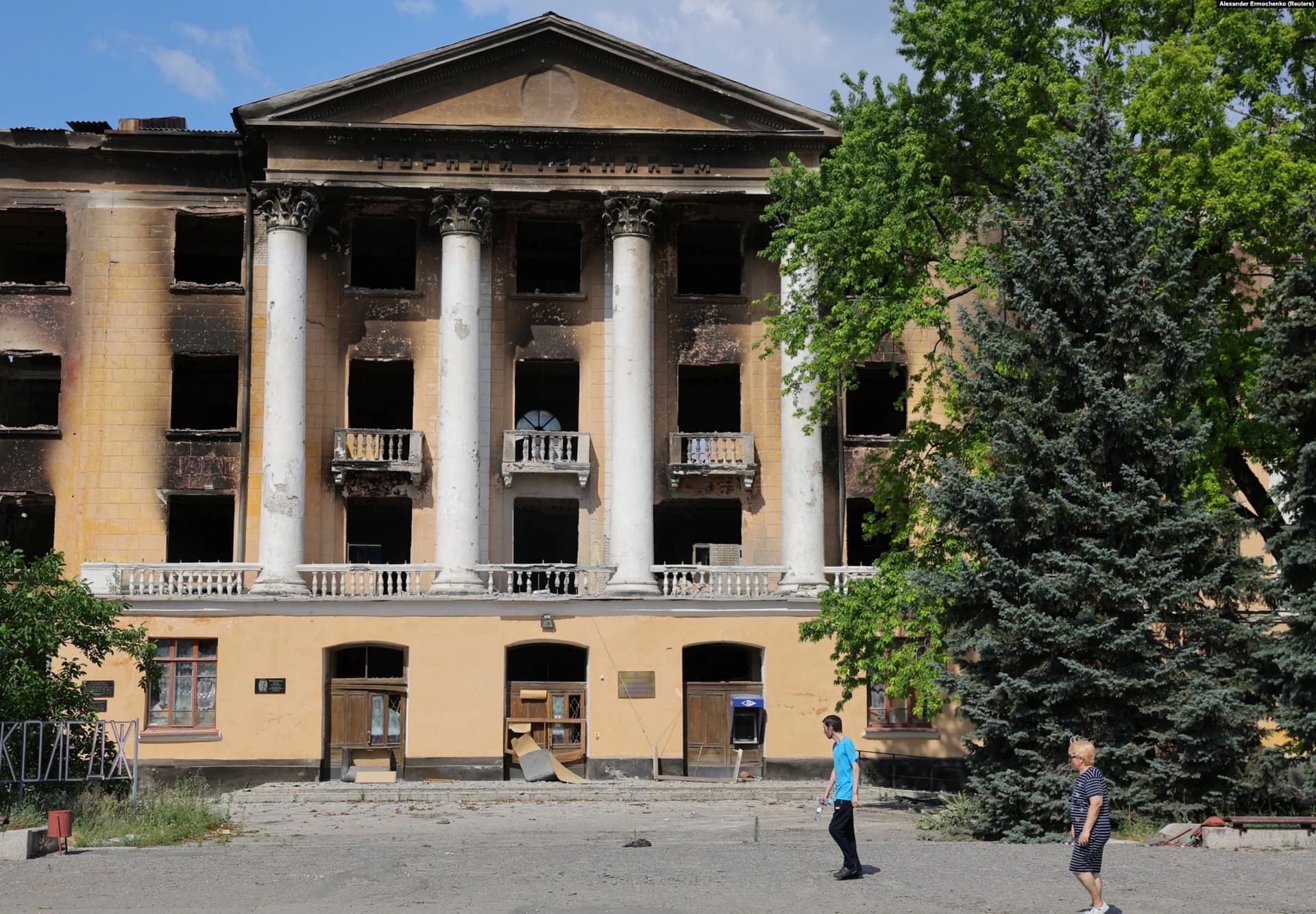 Residents walk past the ruins of the Lysychansk State Mining and Industrial College