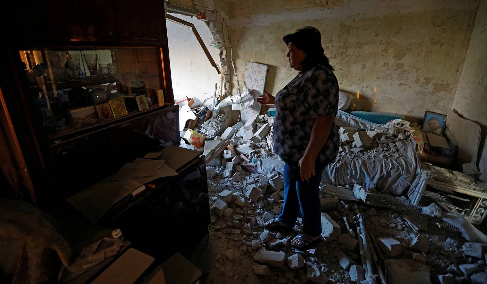 Local resident walks around her neighbours' damaged apartment in Makiivka