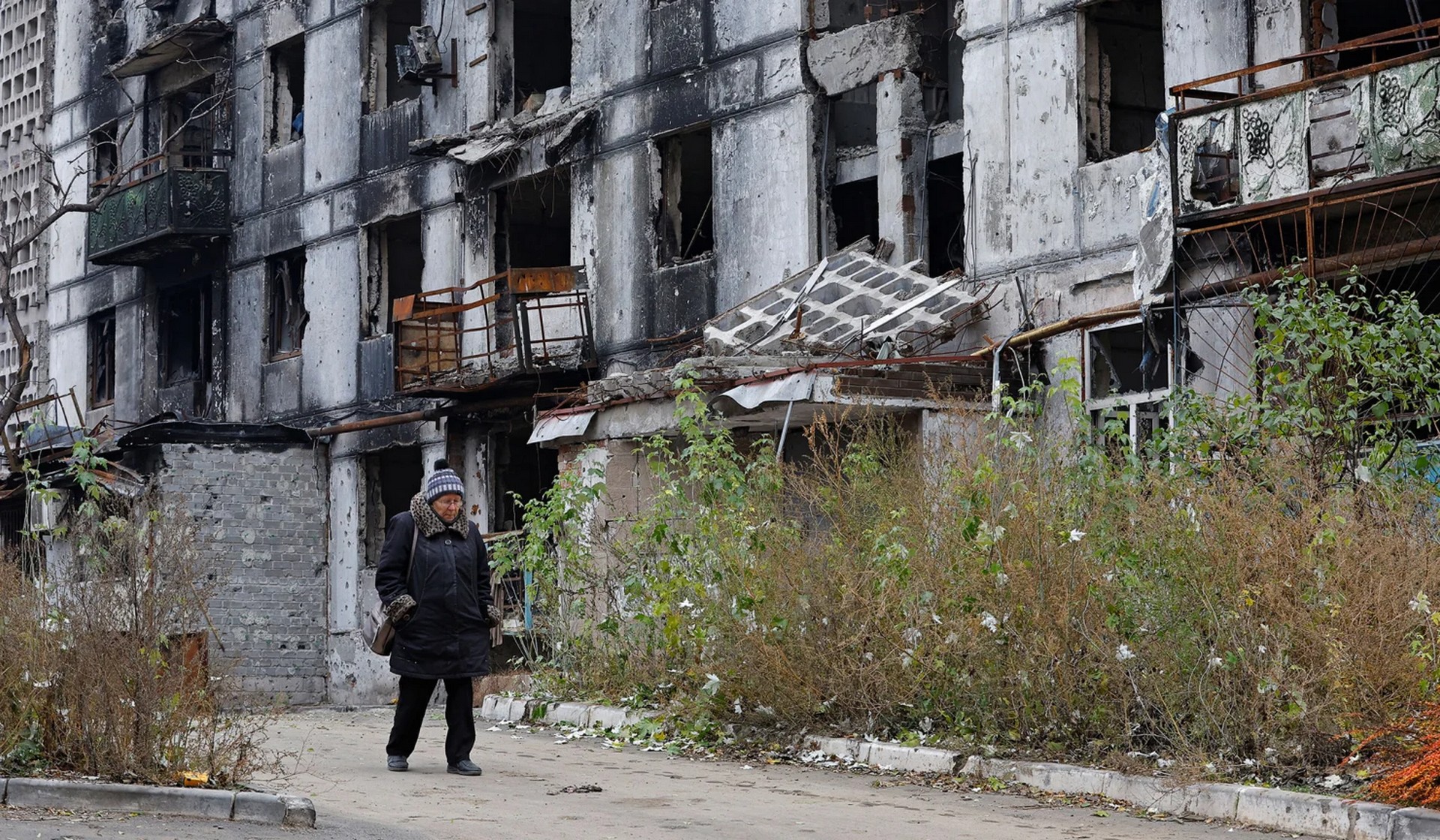 Local resident Tatiana walks past a damaged apartment building in Mariupol