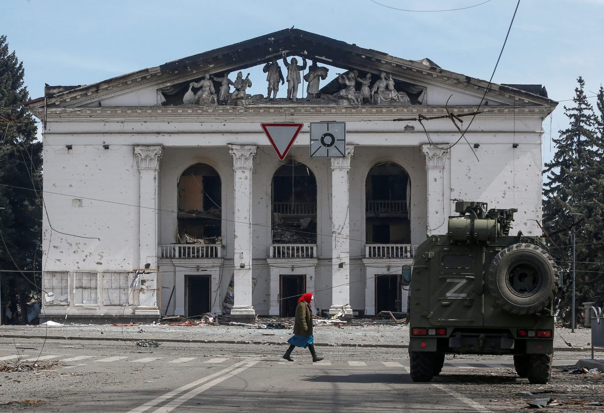 A woman walks past an armoured vehicle of pro-Russian troops in front of the destroyed theatre in the southern port city of Mariupol