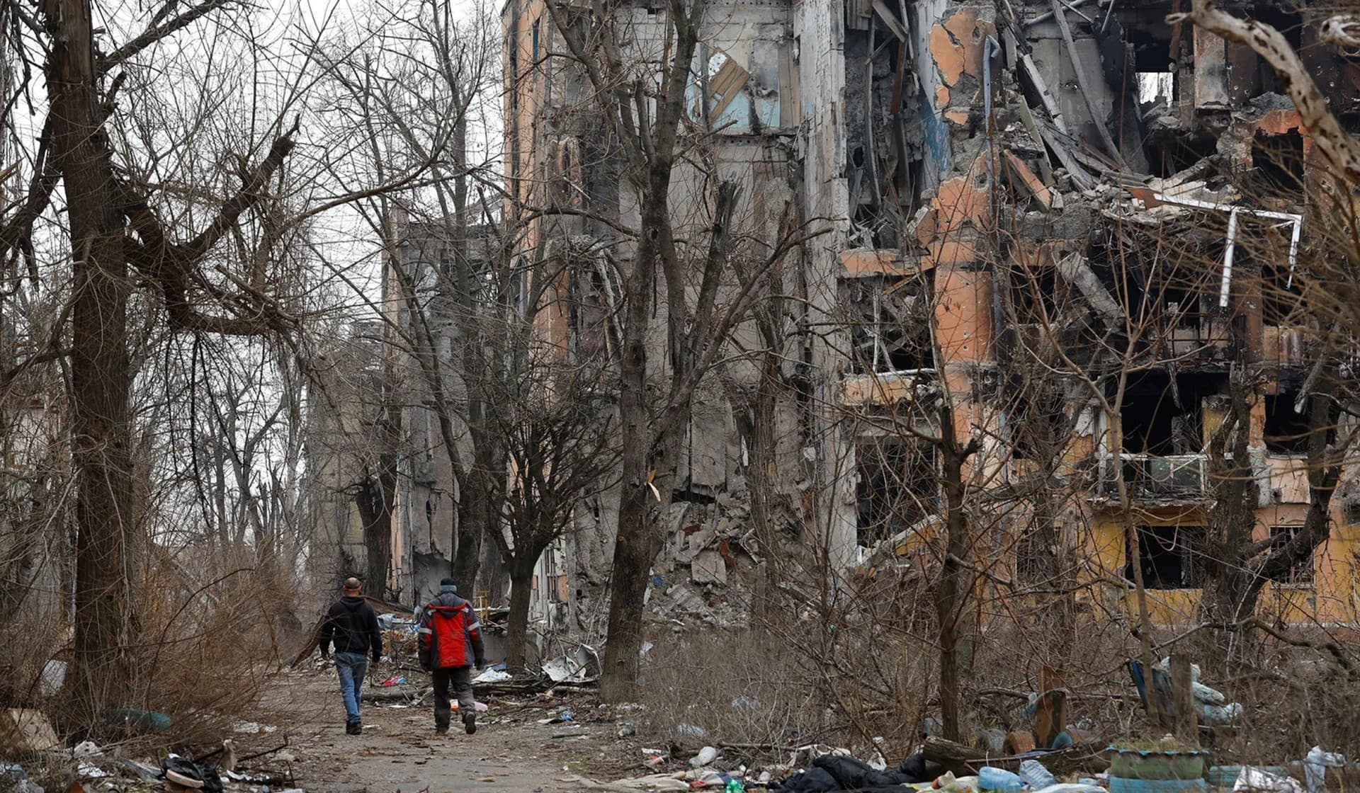 Men walk near multi-storey apartment blocks in Mariupol