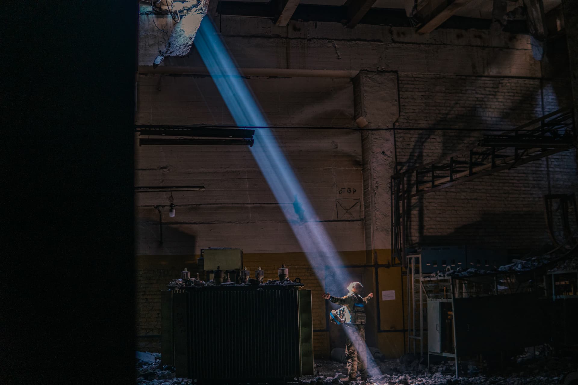 A Ukrainian soldier inside the ruined Azovstal steel plant stands under a sunlight ray in his shelter in Mariupol
