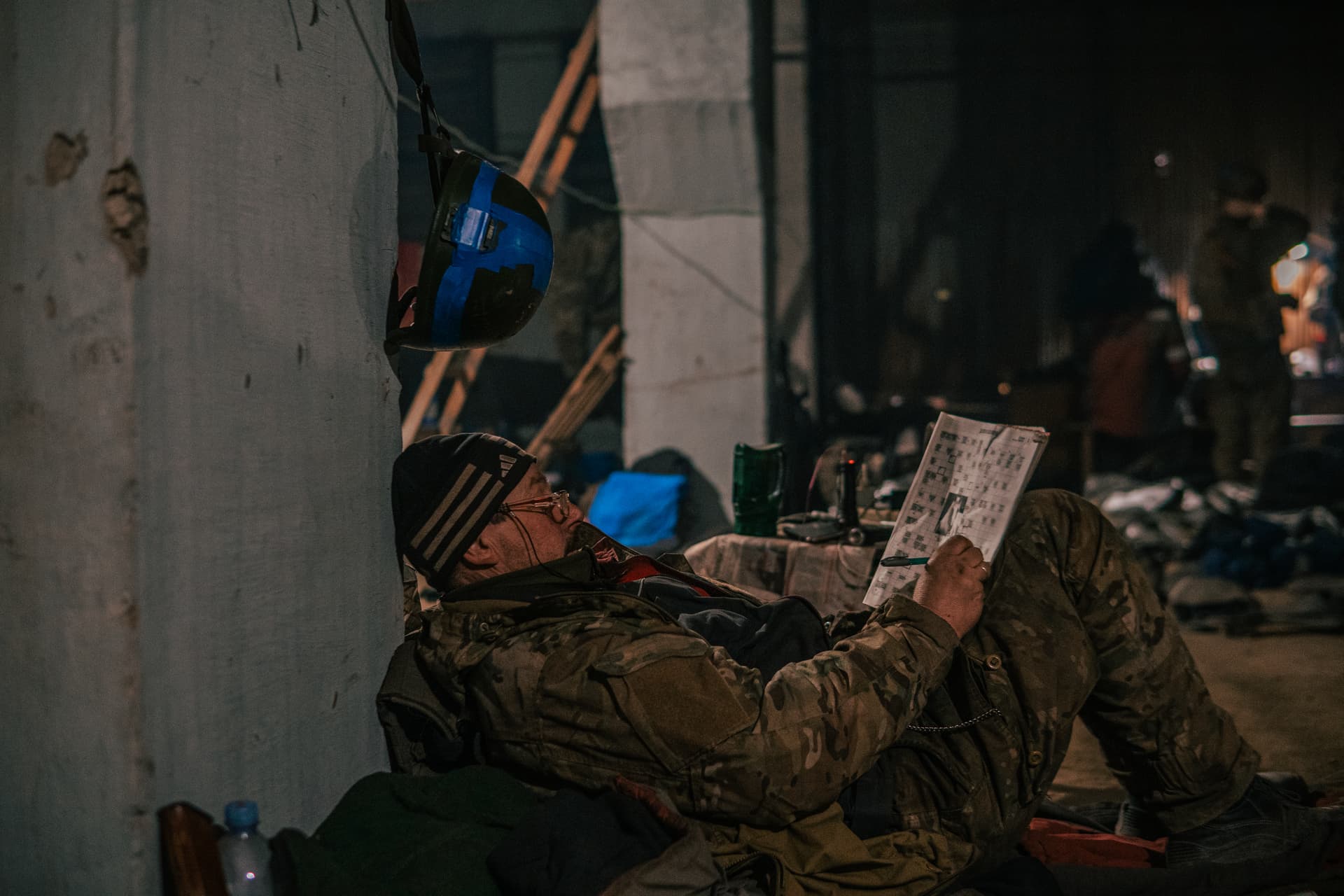 A Ukrainian soldier does crossword as he has a rest in his shelter in Mariupol
