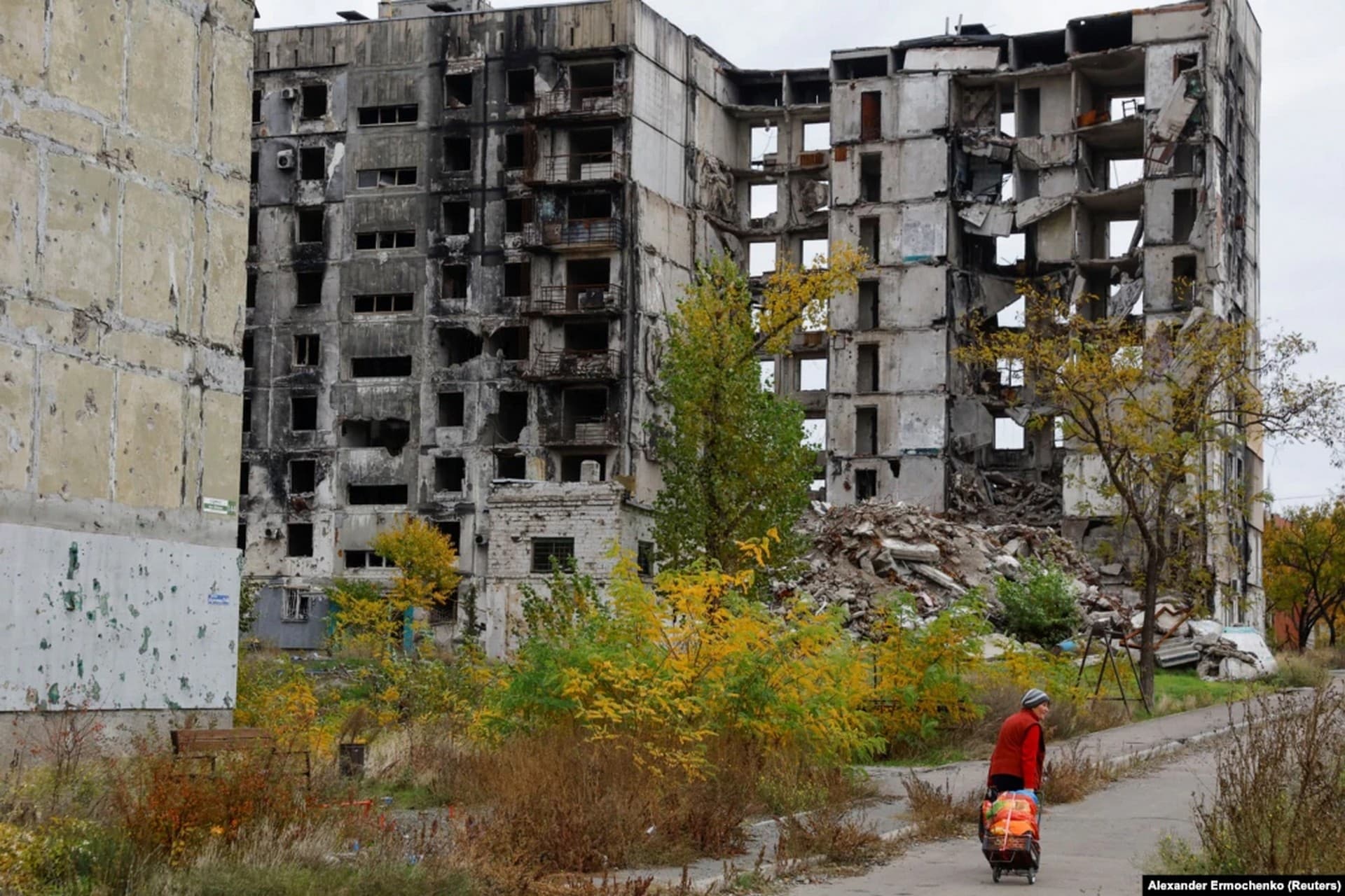 A woman walks past a ruined apartment building on October 29