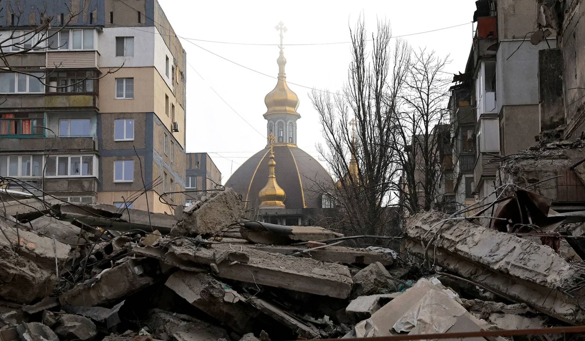 The dome of an Orthodox church seen behind a destroyed building in Mariupol