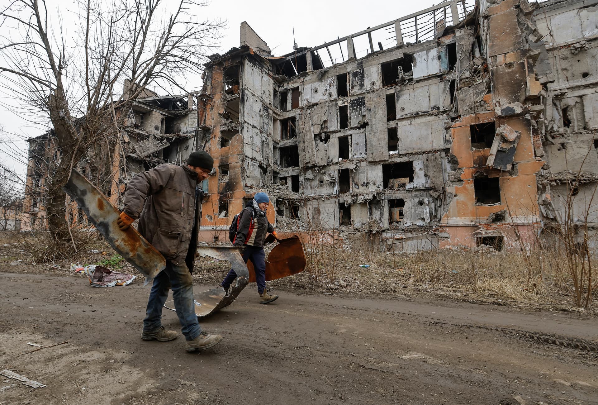 Local residents walk past a destroyed apartment block in Mariupol