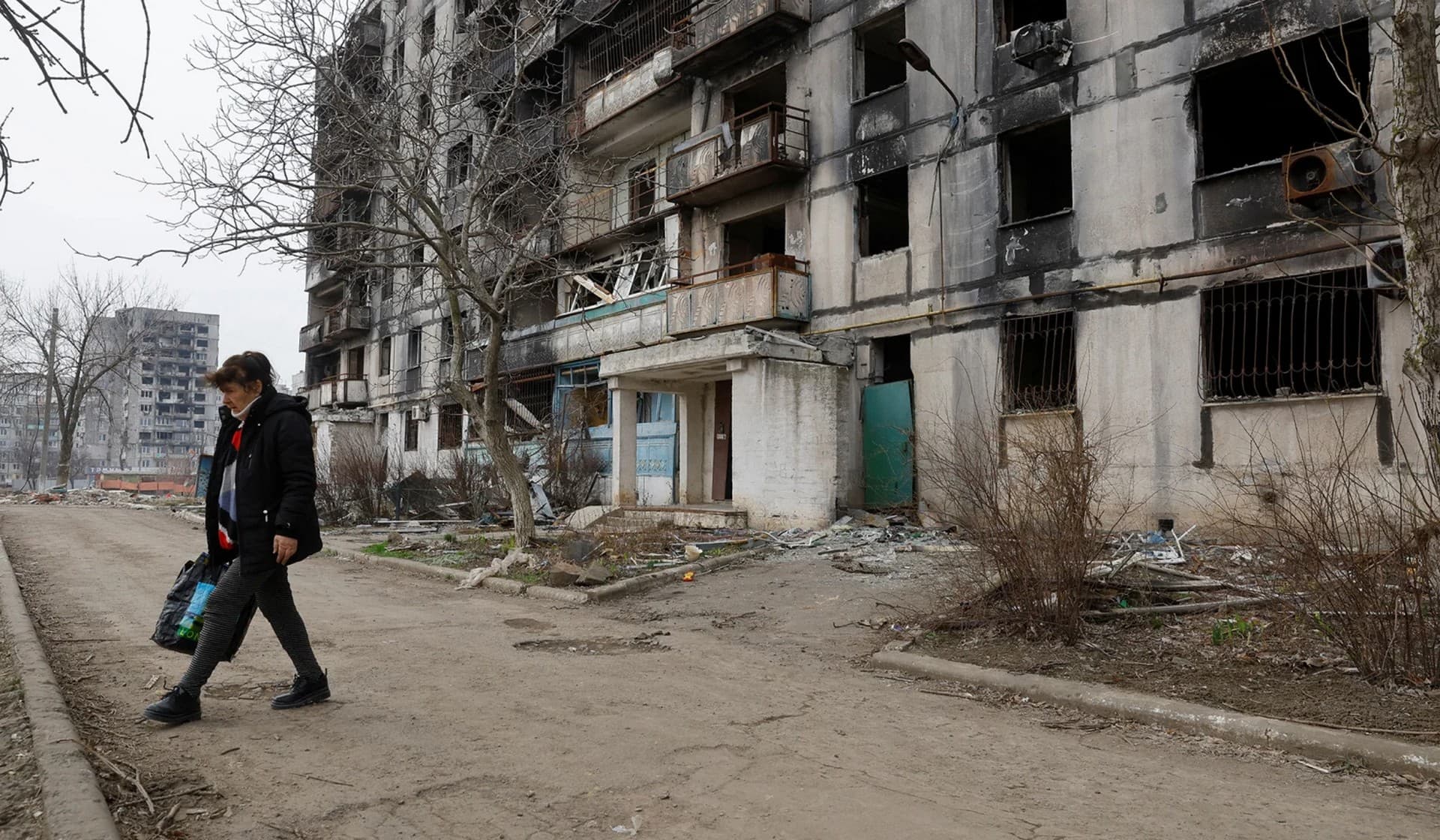 A local resident walks outside a multi-storey apartment block in Mariupol