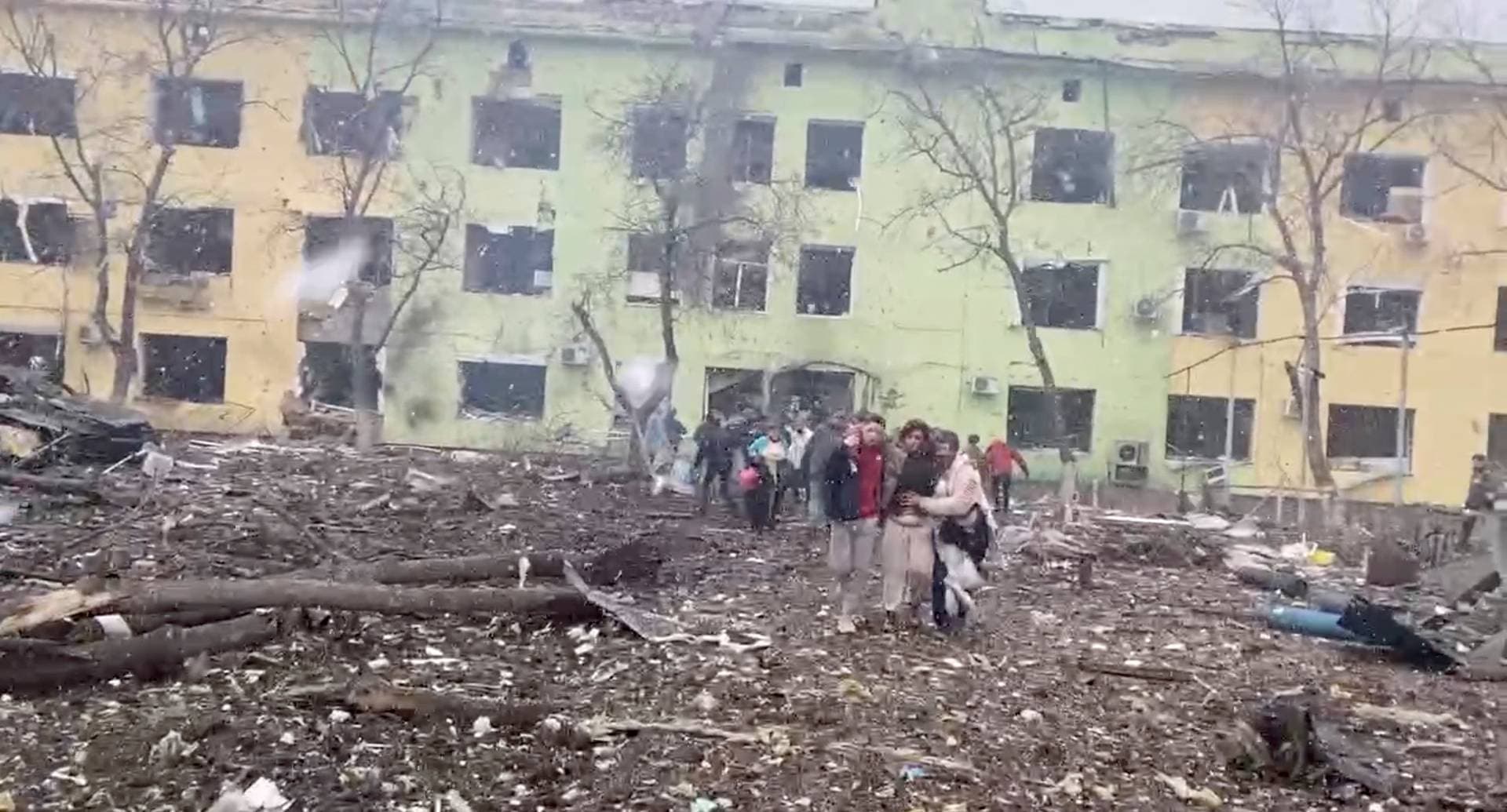 people are helped out of a damaged building of a children's hospital following a Russian air raid in Mariupol
