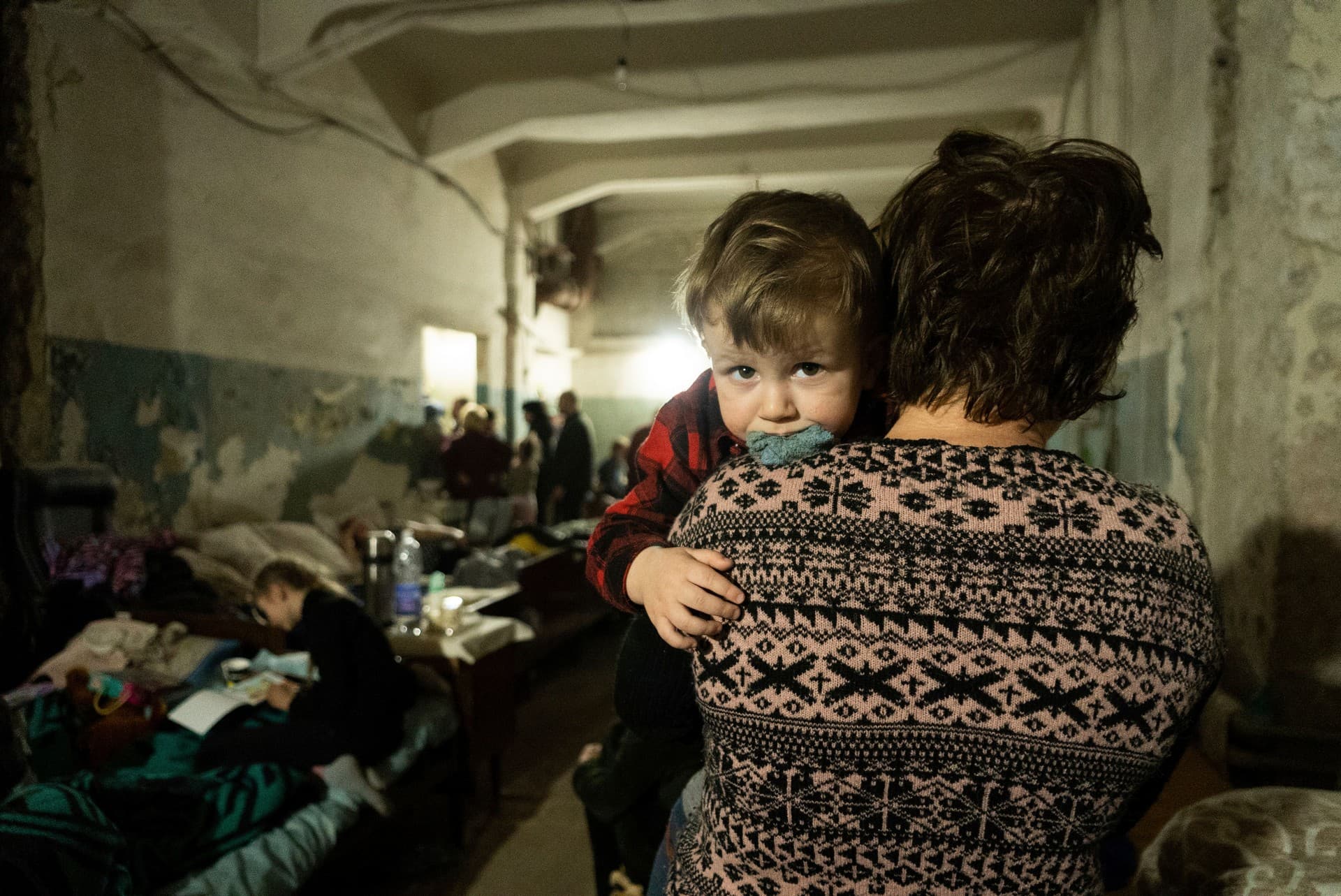 A woman holds a child in an improvised bomb shelter in Mariupol