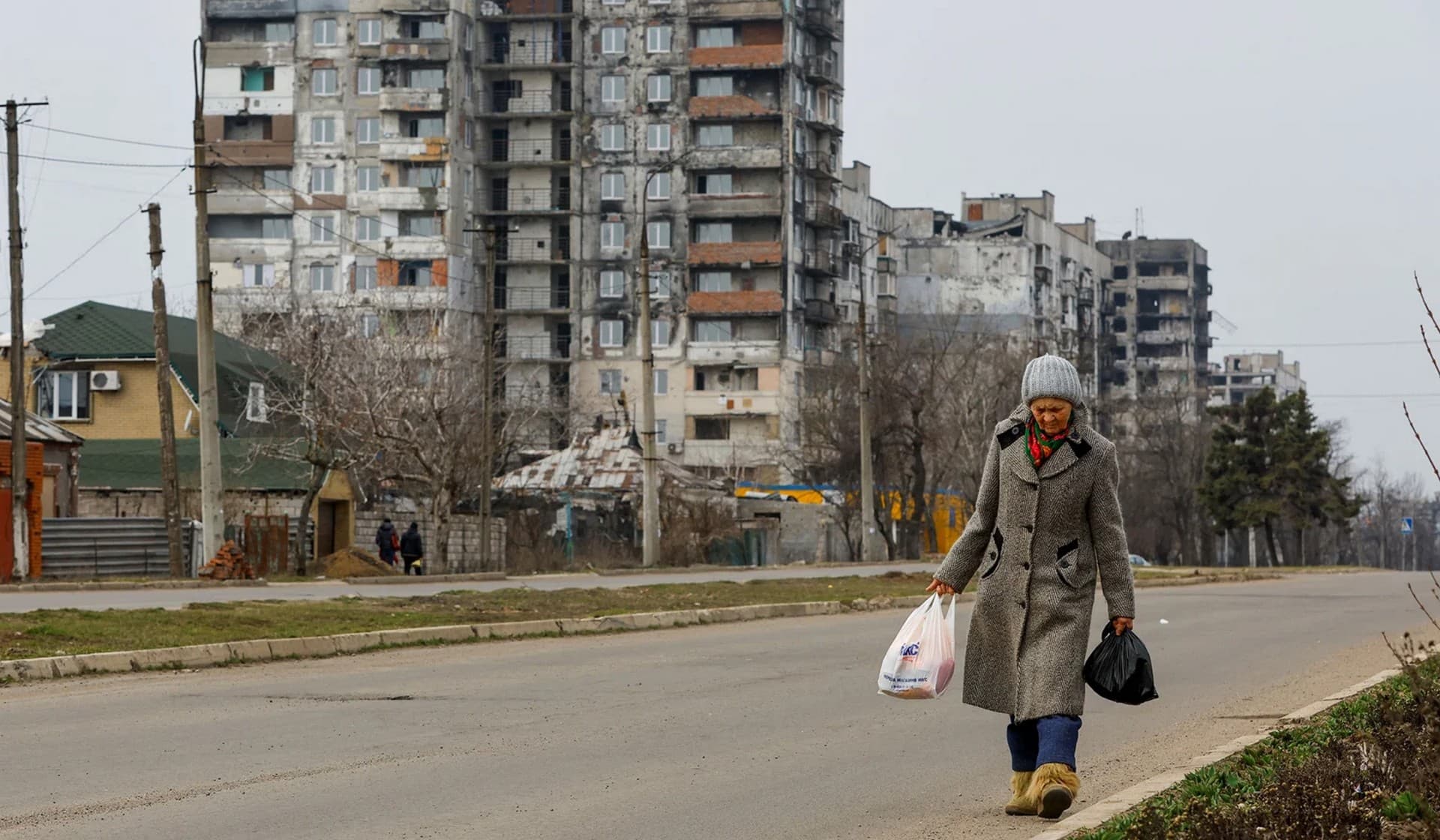 A local resident walks near multi-storey apartment blocks in Mariupol