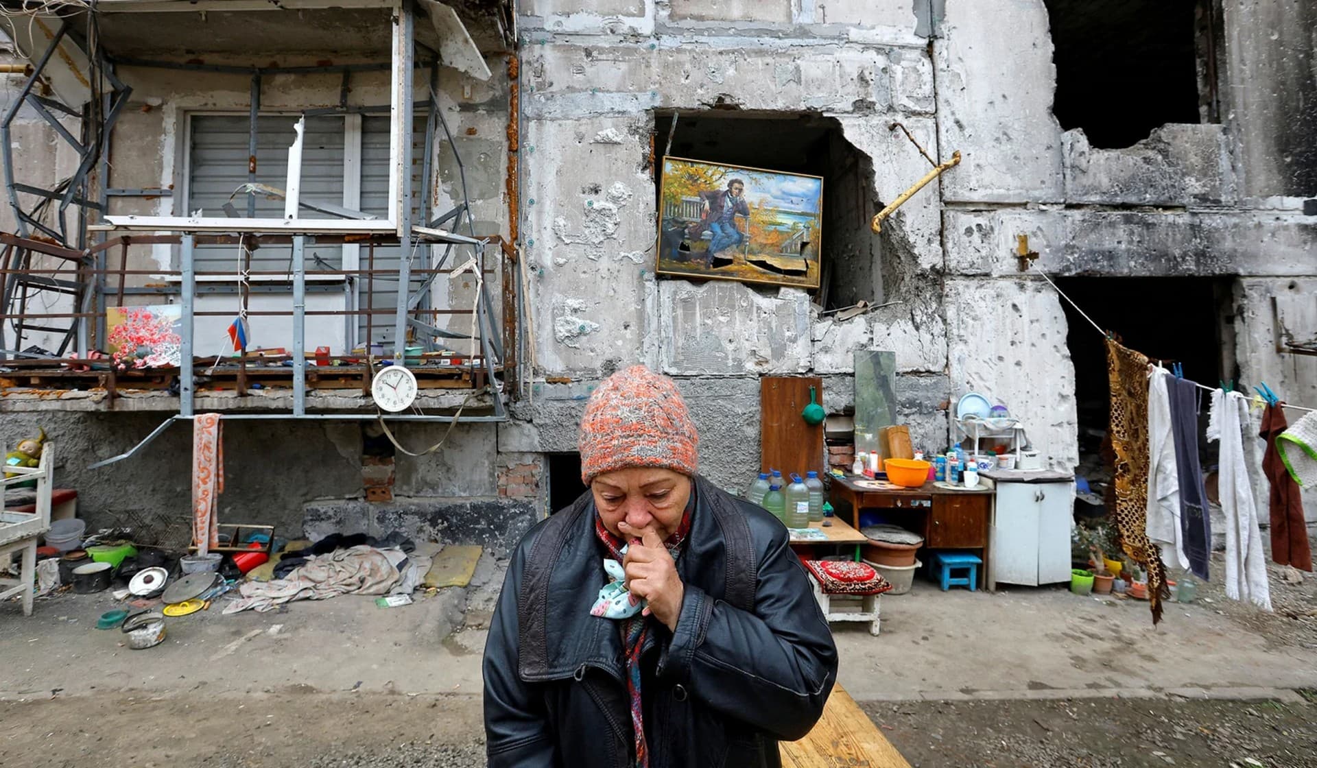 Local resident Galina Shevtsova reacts outside the apartment building where she lives in the basement with her husband Pavel after their flat was destroyed in March in Mariupol