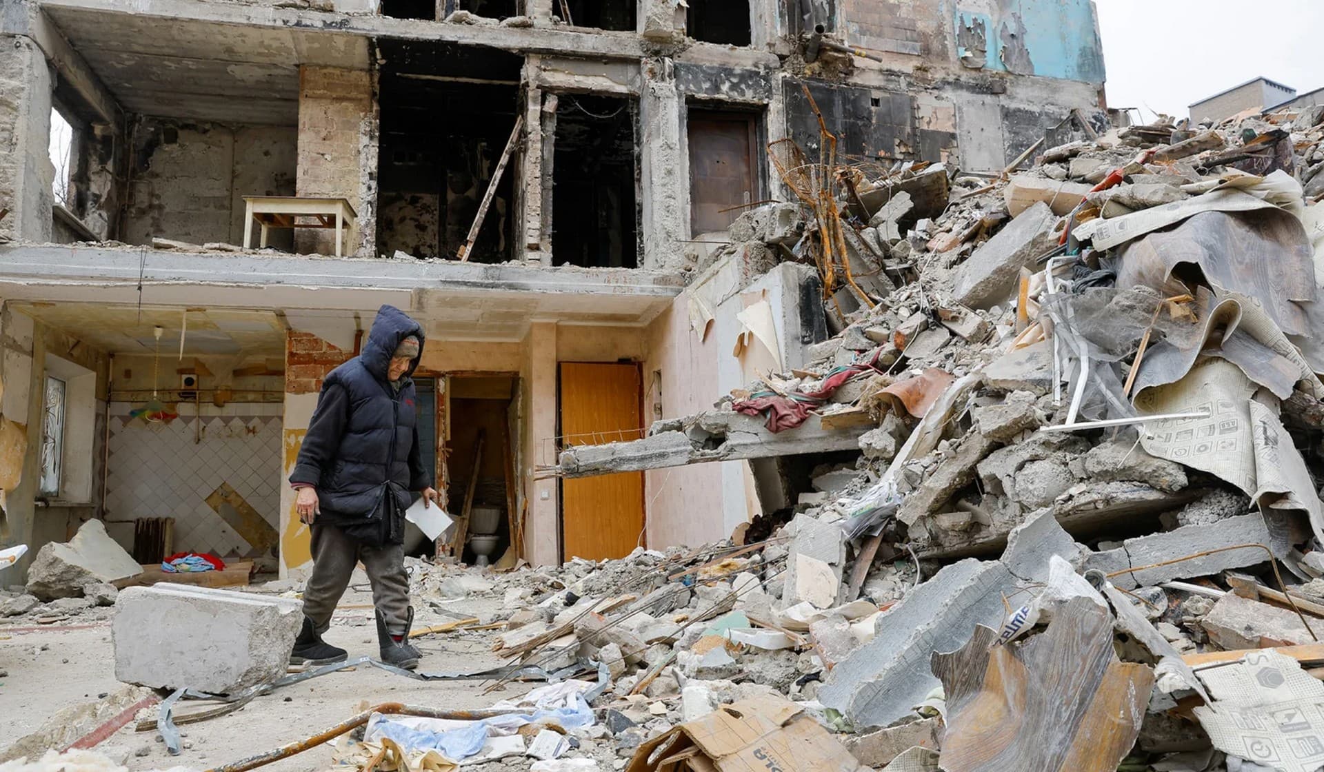 A local resident walks near debris of a residential building in Mariupol