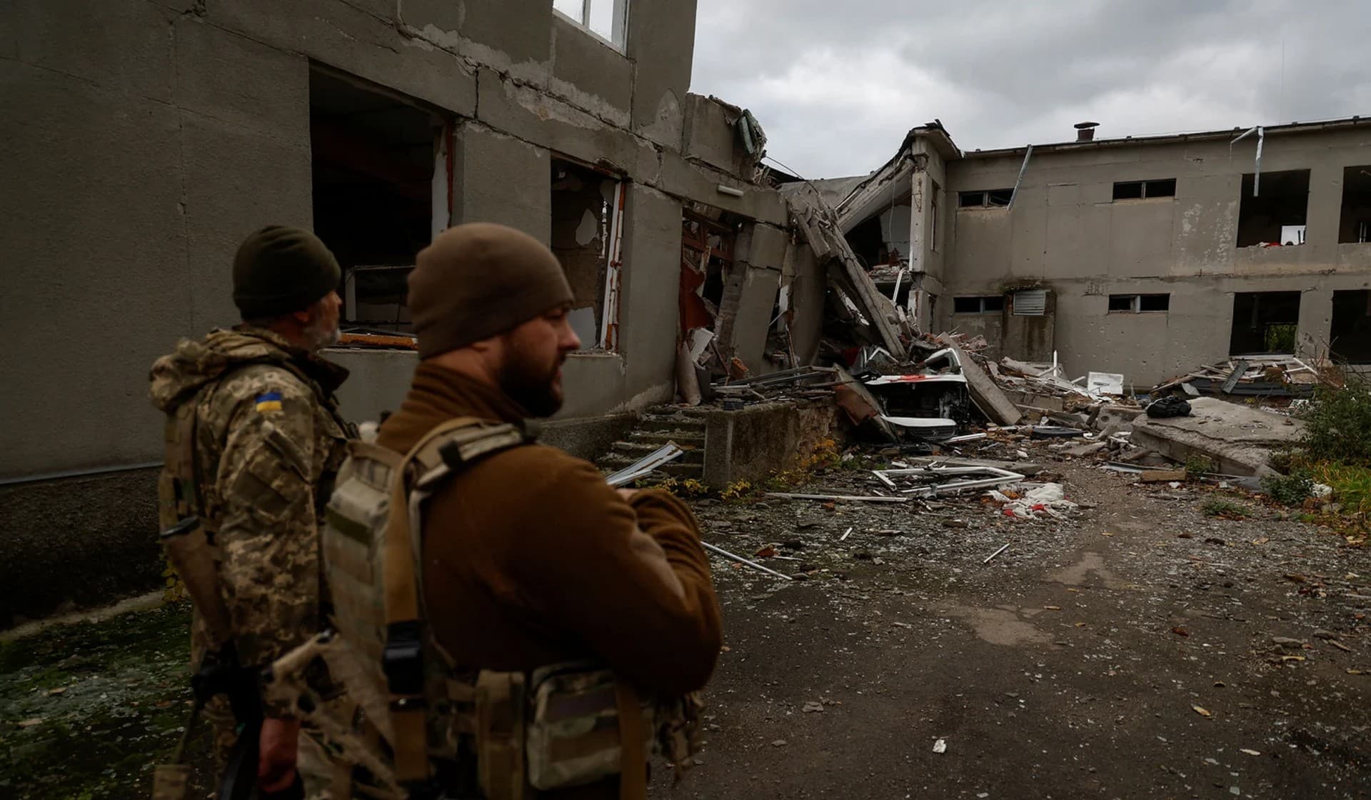 Ukrainian servicemen stand next to a school building destroyed by a Russian air strike in a village near a frontline in Mykolaiv Region