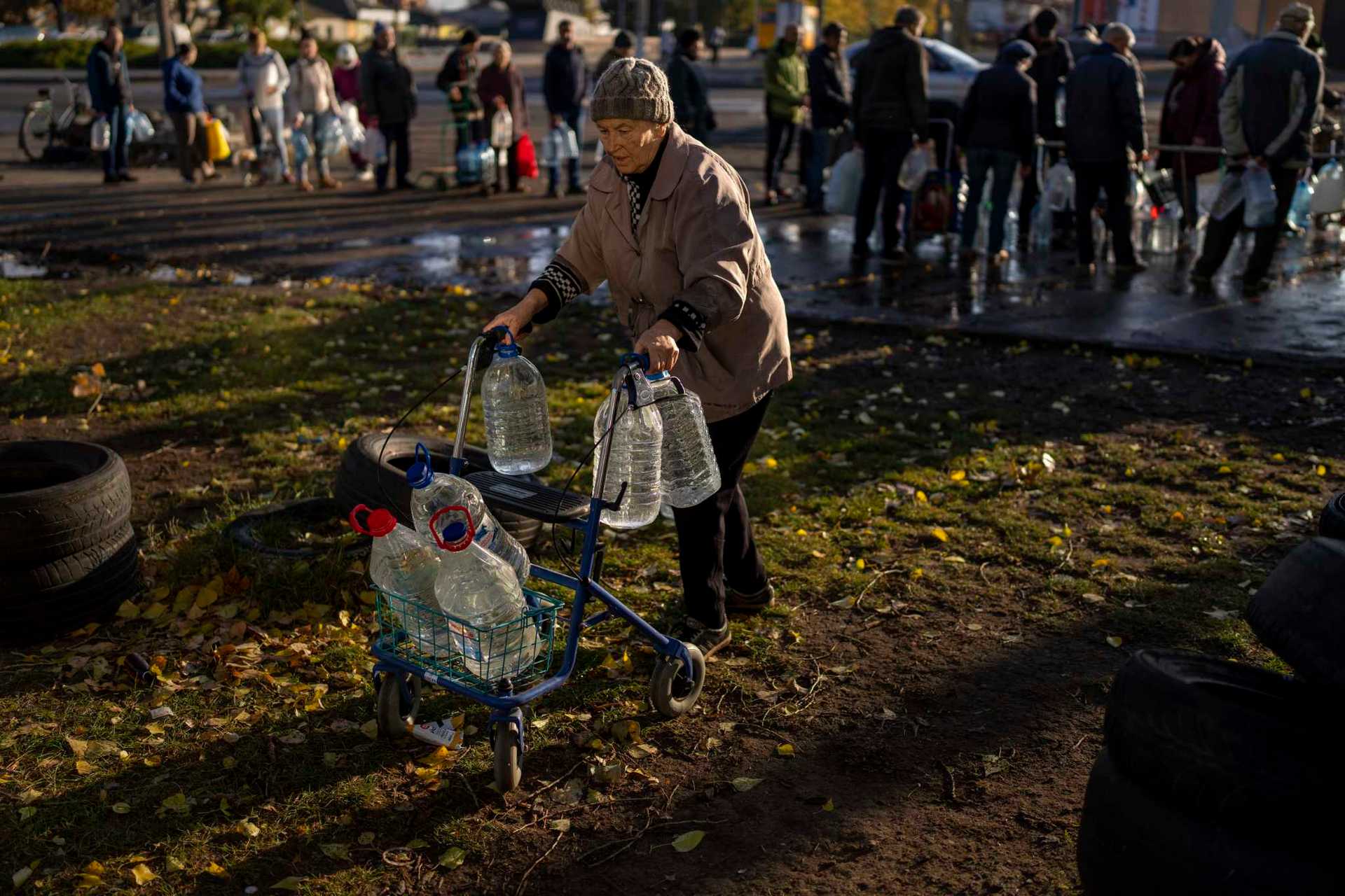 Catherine, 75, pushes her walker loaded with plastic bottles after refilling them in a tank, in the center of Mykolaiv