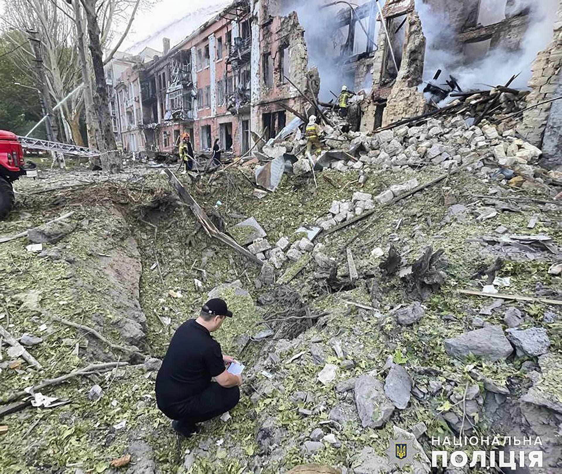 members of emergency services work at a building destroyed by a Russian attack in Mykolaiv