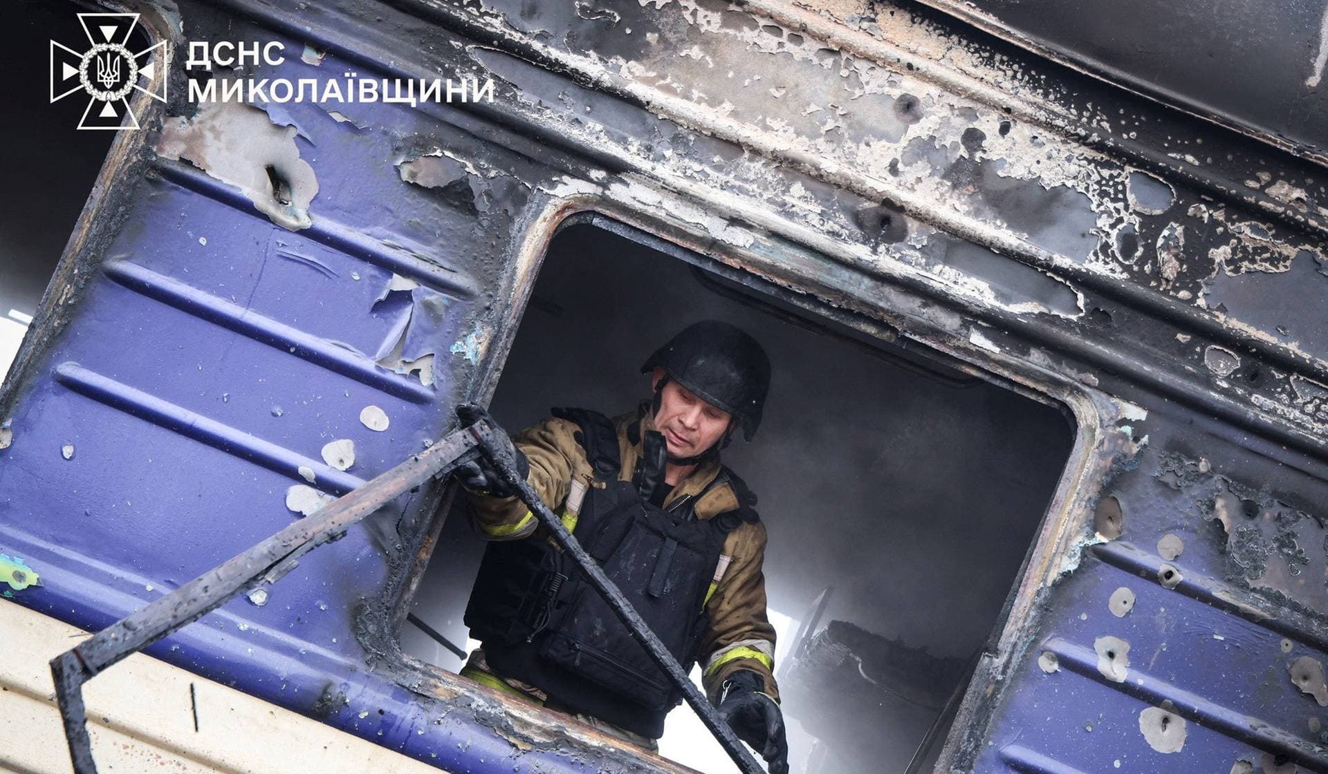 A firefighter works in a passenger train after it was hit by a Russian drone strike at a railway station in Mykolaiv Region