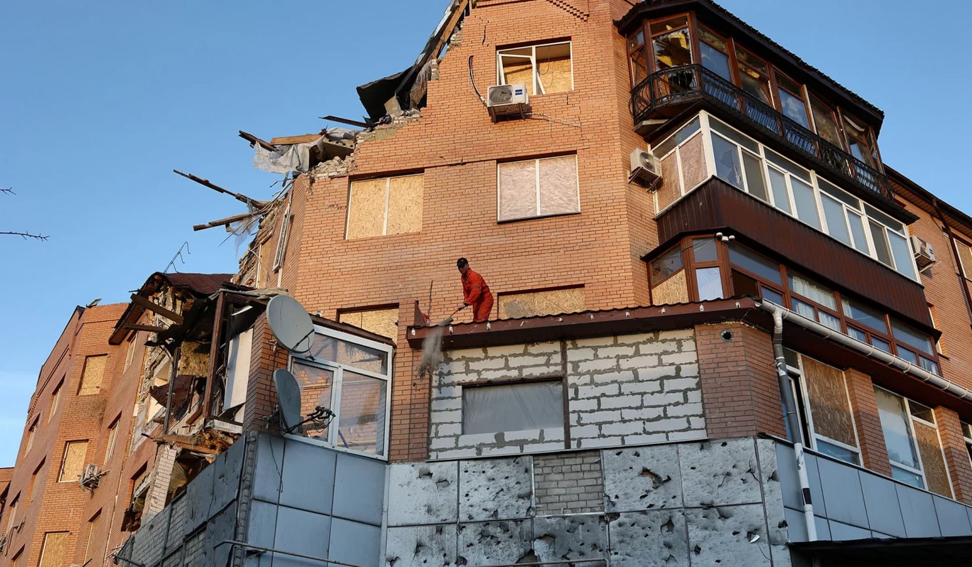 A man cleans rubble at a damaged residential building in Mykolaiv