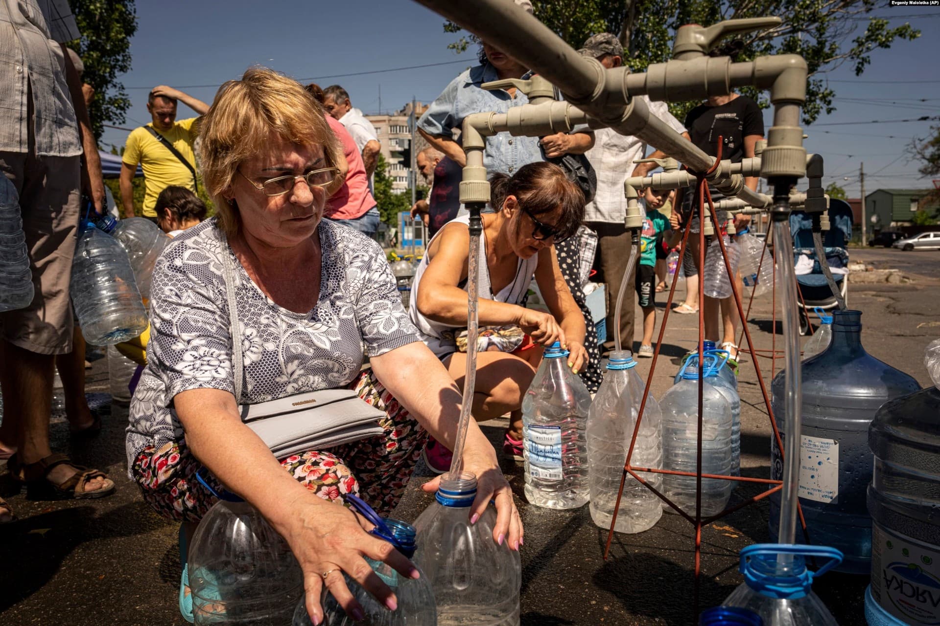 Women fill bottles with water provided by a volunteer organization in Mykolayiv