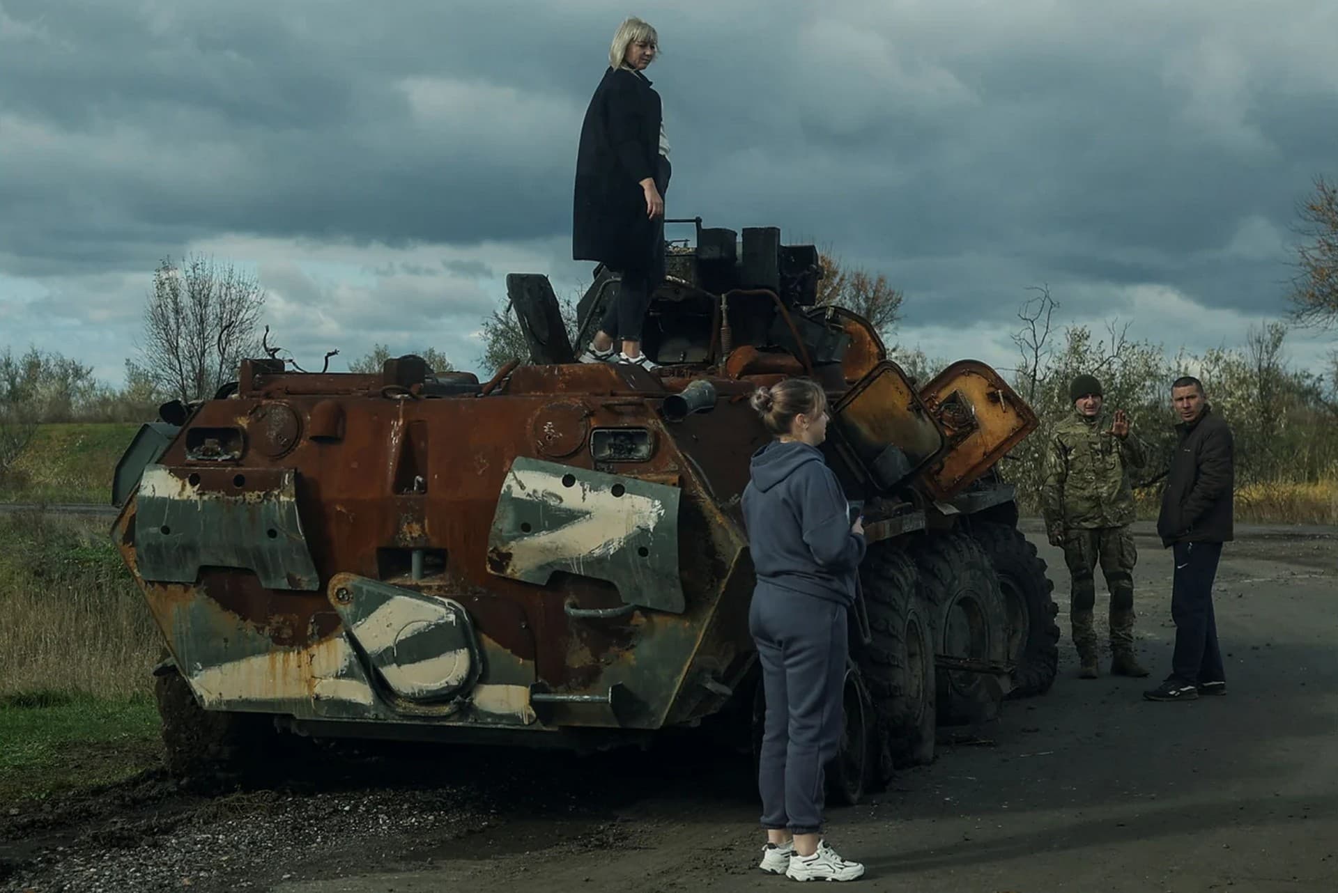 A woman stands atop a destroyed Russian armored personnel carrier in a village near a frontline in Mykolaiv Region